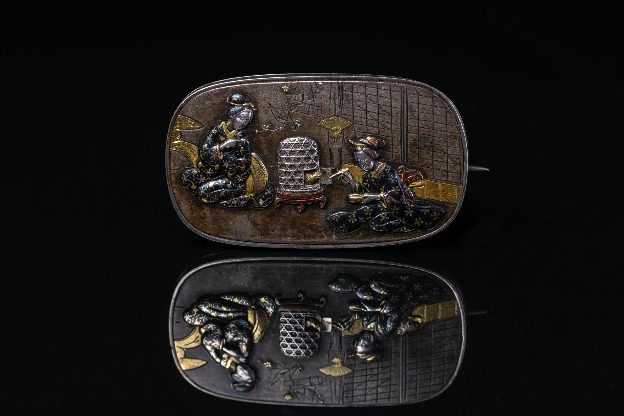 This exquisite antique Japanese shakudo rectangular brooch is a fine example of Japanese mixed metalwork from the Meiji period (1868-1912). The brooch is crafted using a combination of metals including gold, silver and copper, materials used in a