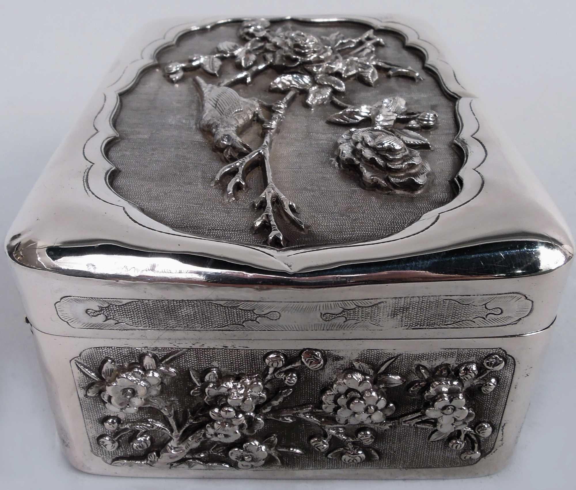 Scatola d'argento giapponese Meiji, 1890 circa. Rettangolare con angoli curvi. I lati della scatola presentano uccelli cesellati e incisi tra rami in fiore e bambù in cornici rettangolari. La parte superiore della copertina presenta la stessa
