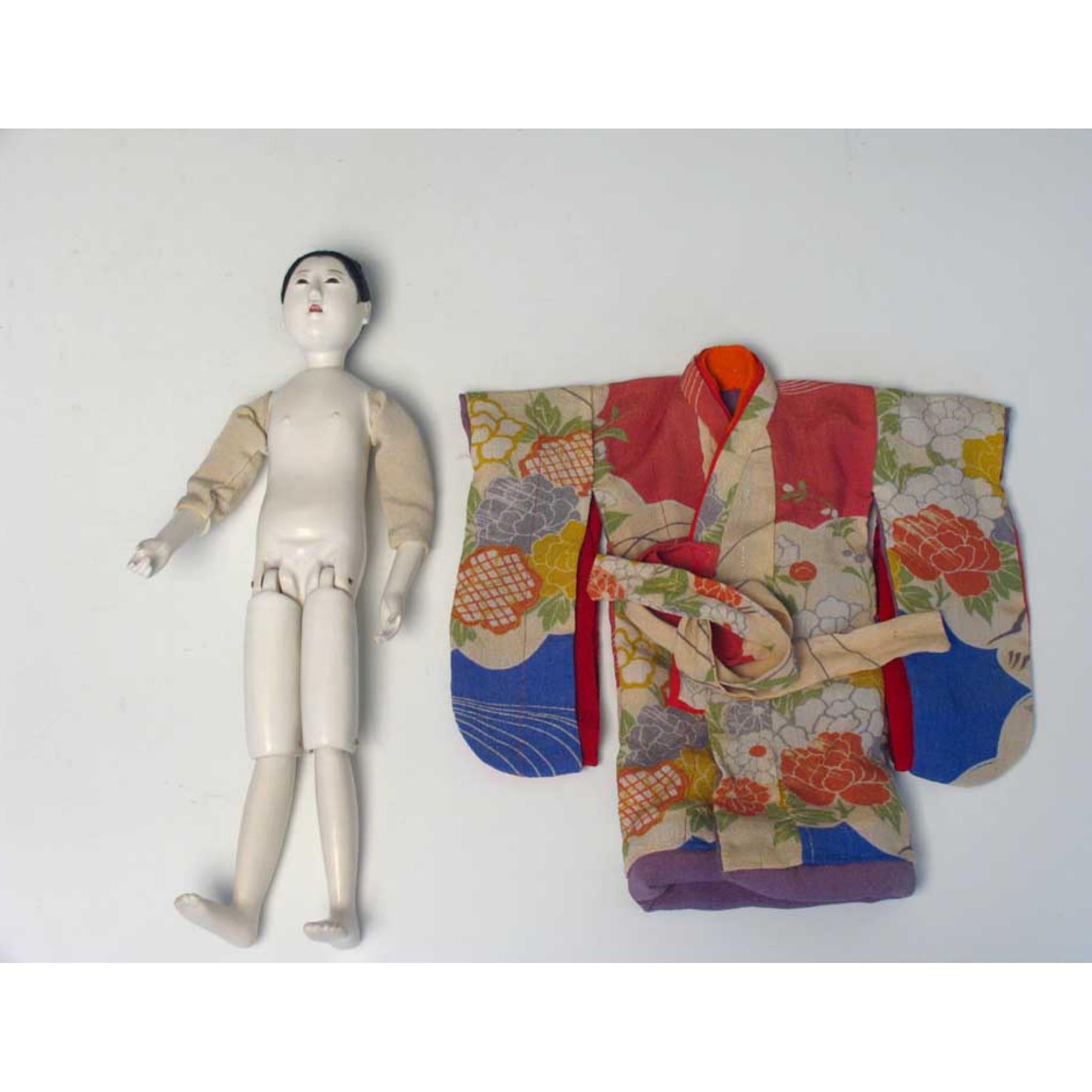 Japanese Mitsuore ningyo of a girl, a jointed costume doll crafted of wood and covered in multiple layers of burnished gofun, made to stand as well as kneel, fabric and wire upper arms to facilitate costuming, a beautiful modeled face with open