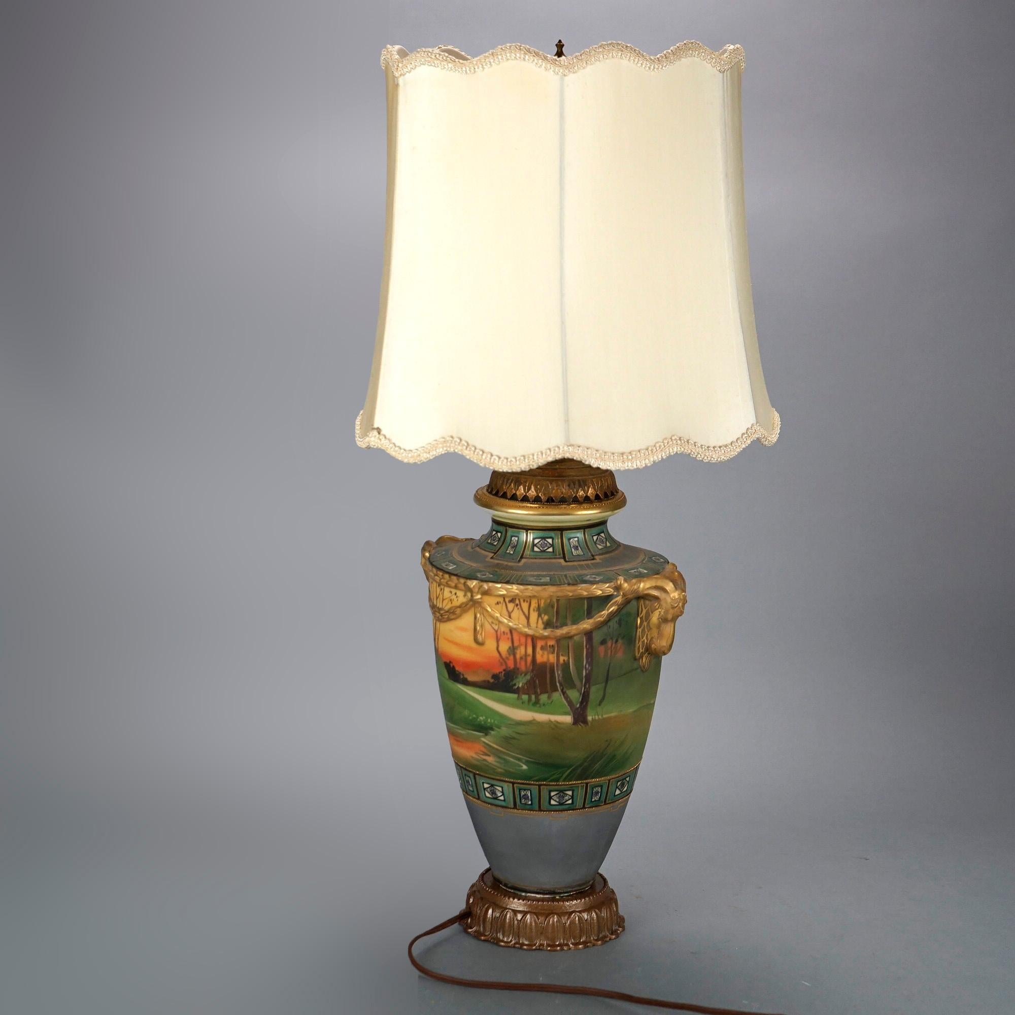 An antique table lamp offers Japanese Nippon urn form base with hand painted scenic decoration, double ram form handles and gilt highlights throughout, raised on foliate cast base, c1920

Measures- 26.75'' H x 12.25'' W x 12.25'' D.

Catalogue Note: