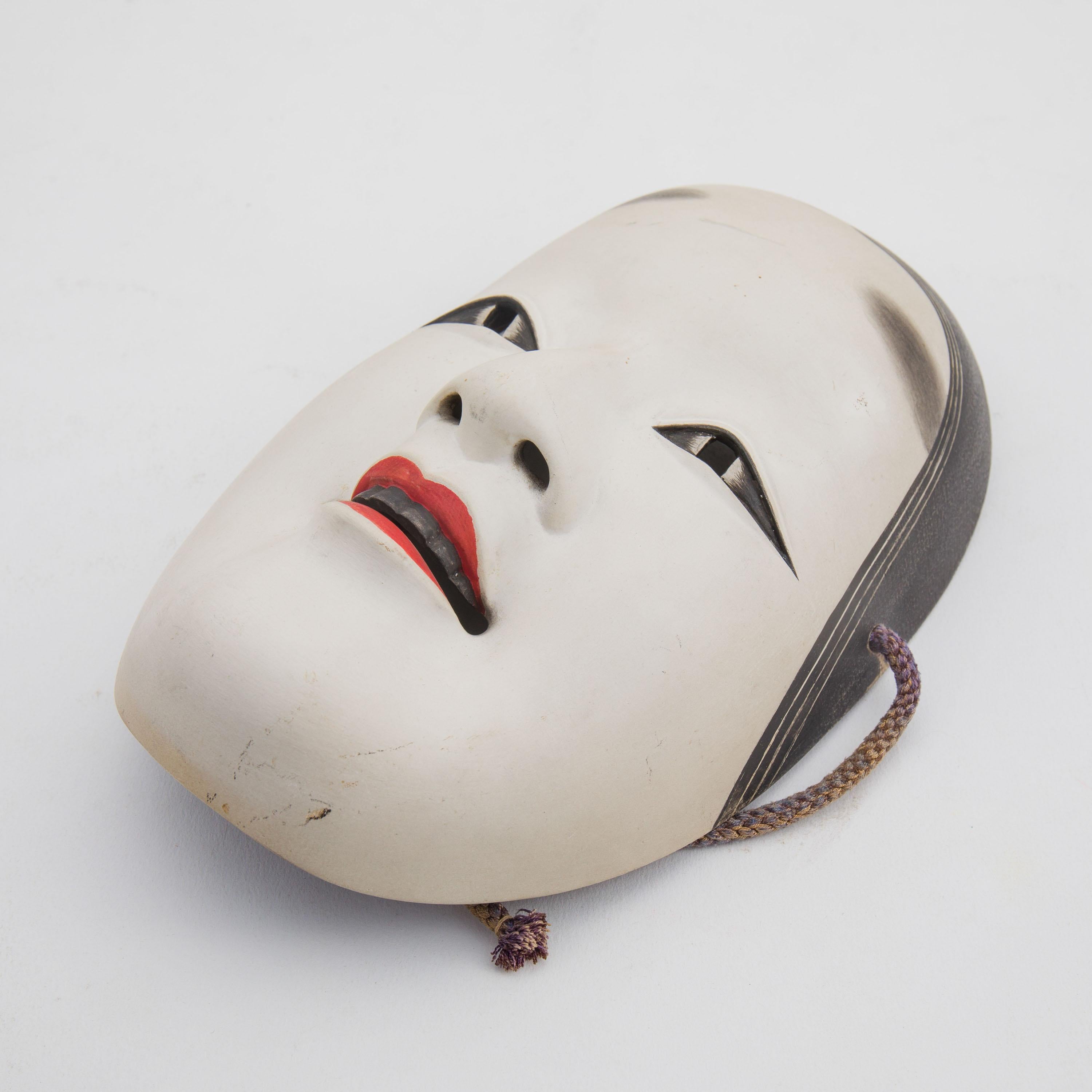An antique hand-carved and hand-painted Japanese Noh theatre mask, depicting a young female character (onna men). Noh Masks have been described as being like 