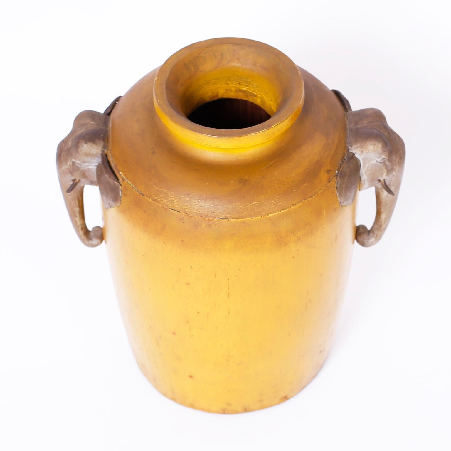 Antico vaso o recipiente in legno del periodo Meiji giapponese con una sorprendente vernice gialla invecchiata e decorato con teste di elefante in legno intagliato con orecchie e zanne in ottone martellato.