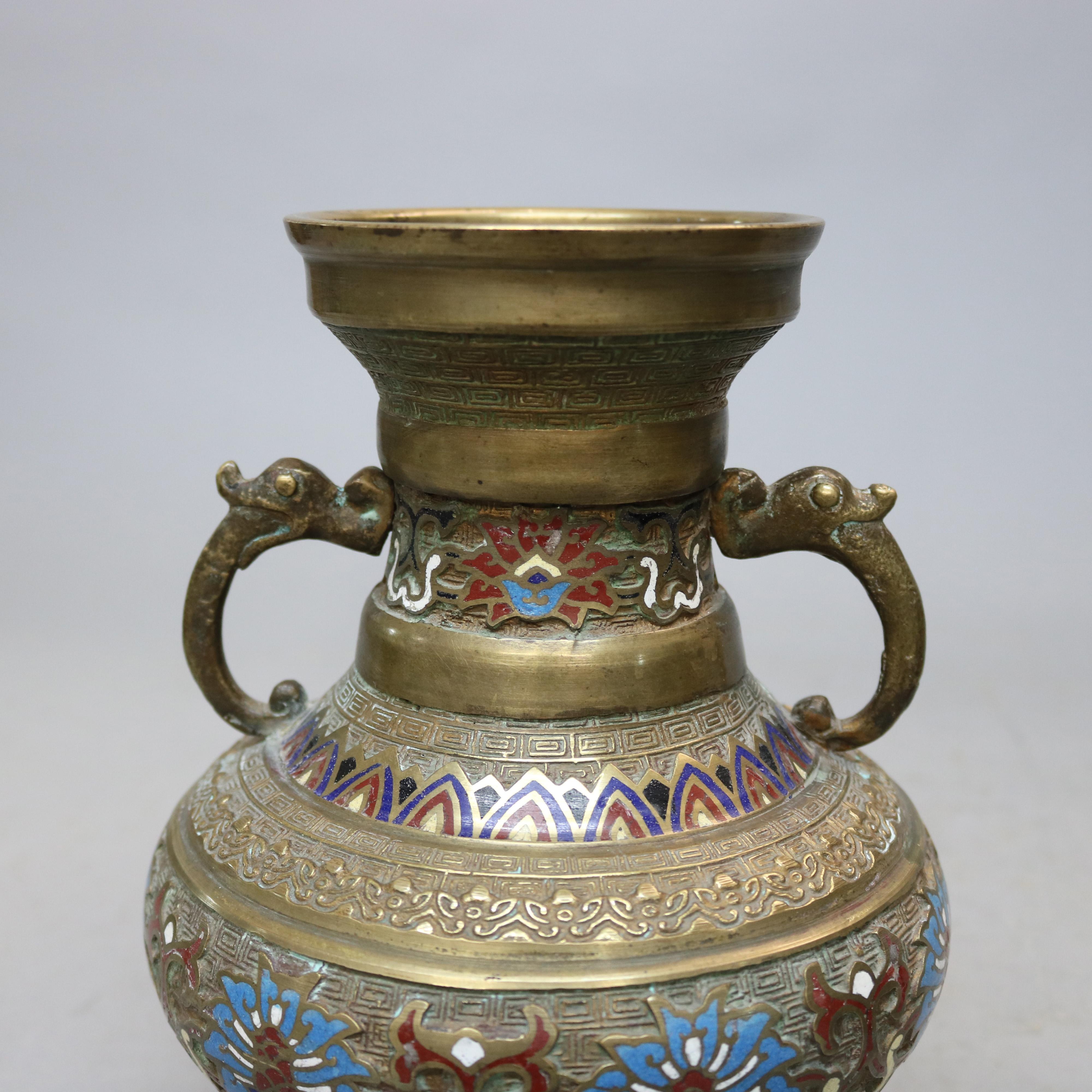 An antique Japanese Persian style vase set offers Champlevé enameled bronze urn form vessels with figural double handles, decorative bands to include stylized floral, Egyptian reed, and geometric elements, circa 1900

Measures: 9.5