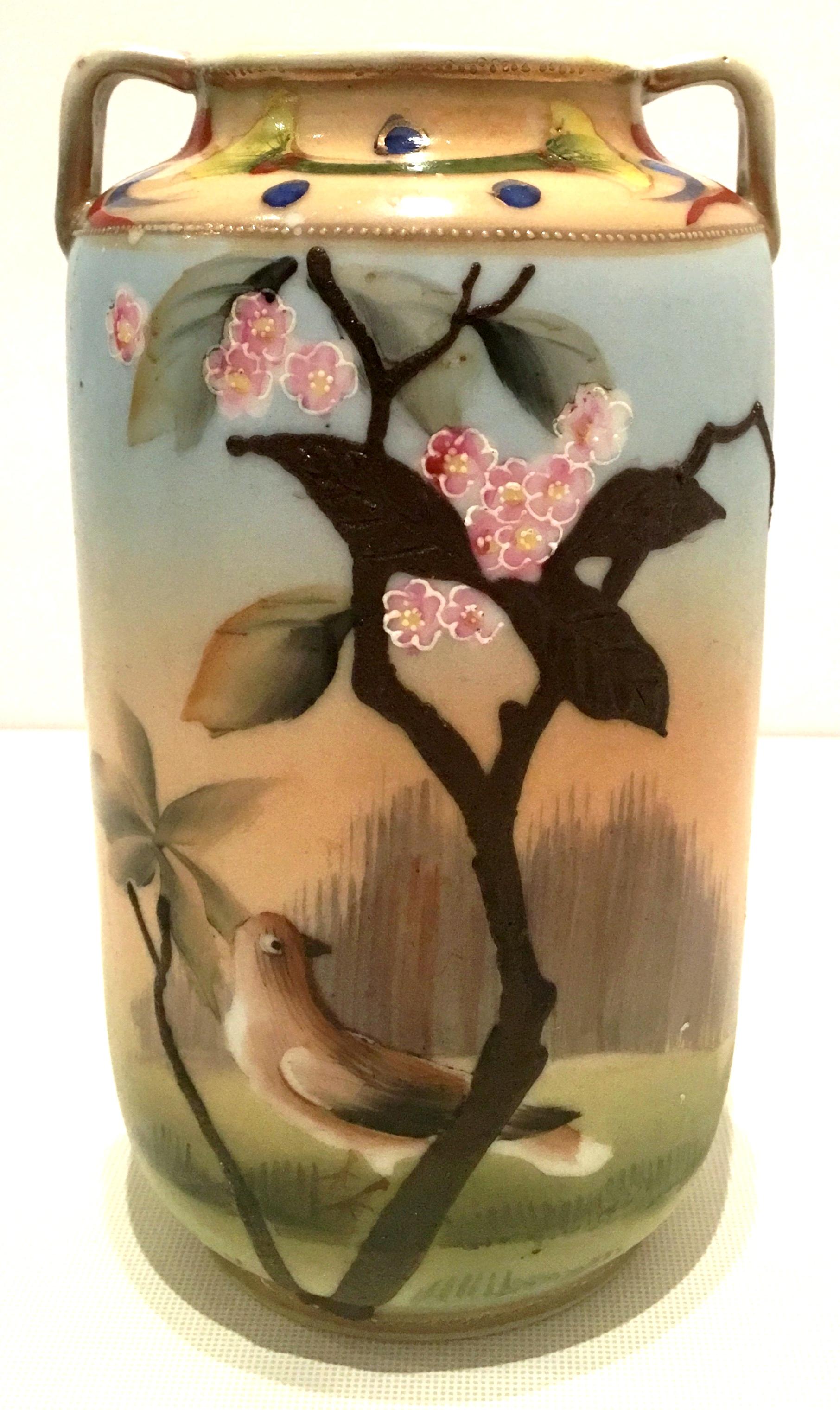 Antique Art Nouveau Japanese hand-painted moriage, 22-karat gold detail two- handle vase. Features a pastel body with raised brown tree and gold raised bead detail. Signed on the underside in green, hand-painted Nippon.