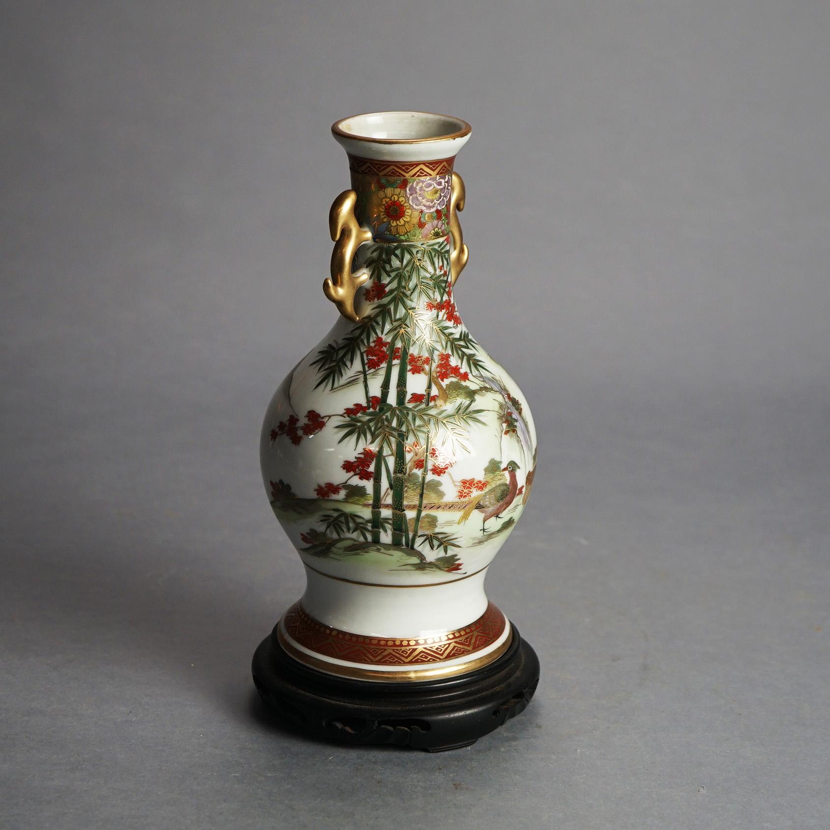 Vase à double anse en porcelaine peinte à la main et dorée de Satsuma avec scène de jardin sur pied en bois, vers 1920

Mesures - 11 