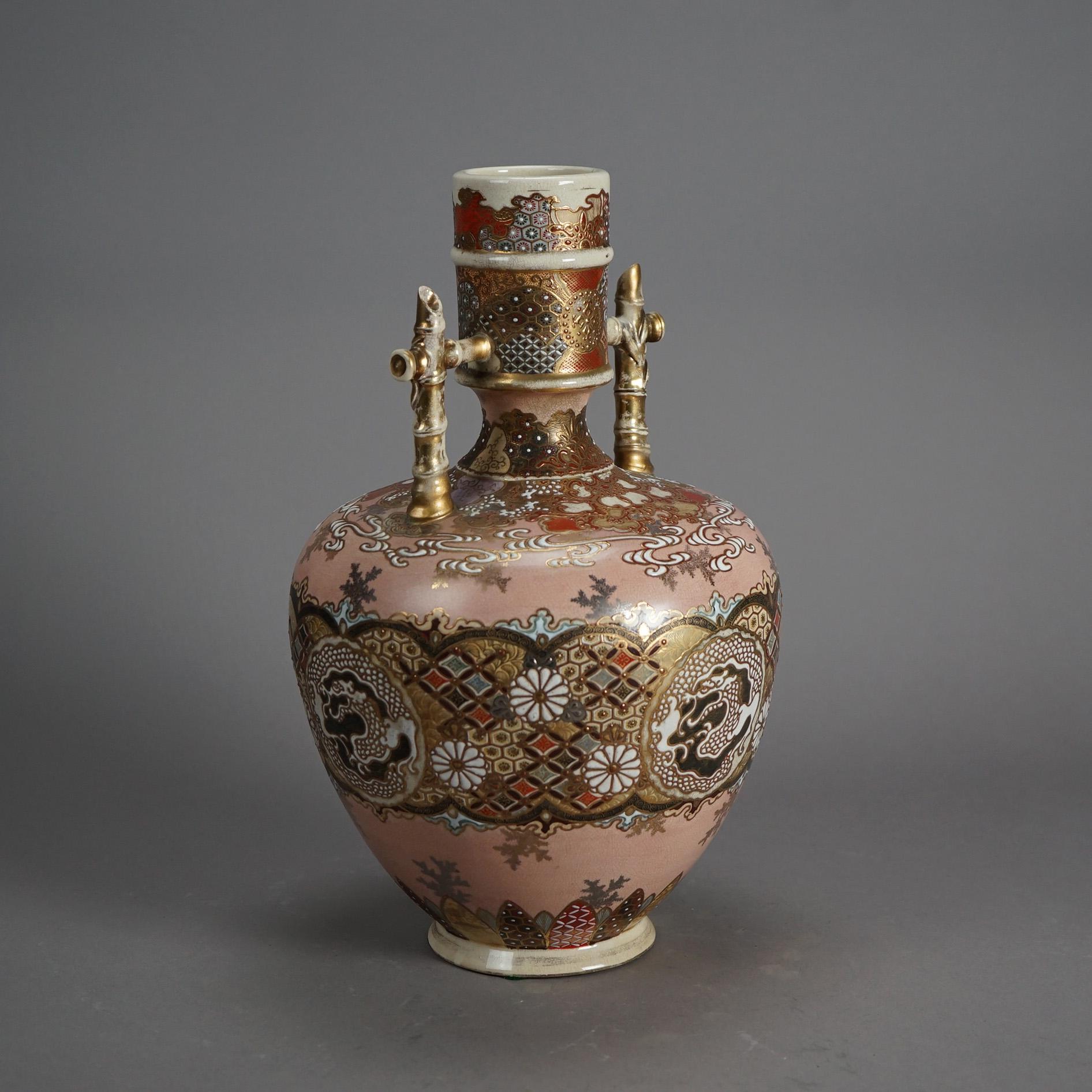 An antique Japanese Satsuma Meiji bottle vase offers porcelain construction with flanking bamboo form handles, hand gilt and painted floral, foliate and dragon design, signed as photographed, c1910

Measures- 15.5''H x 9.5''W x 9.5''D