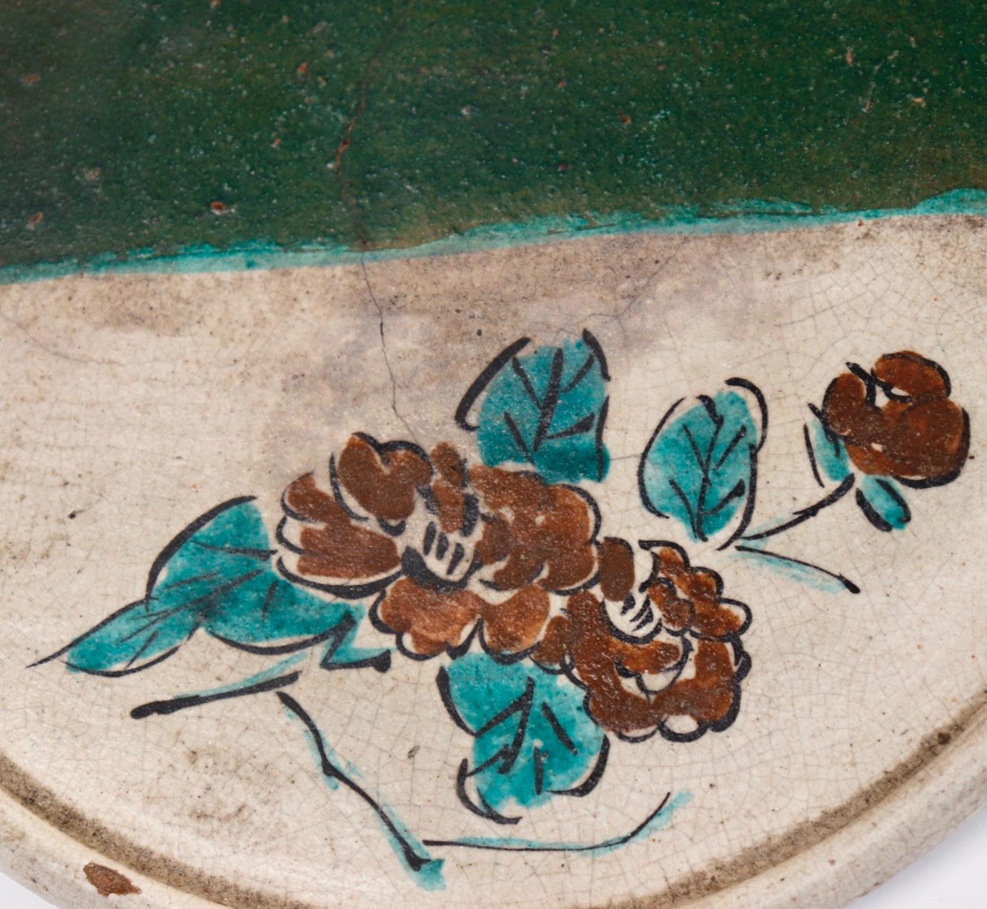 Japanese Abura-zara (oil plate), Seto ceramic plate used to catch oil drippings from lanterns, simple flat, round dish with slightly raised edge, one half covered in an Oribe-style green glaze, with an iron-oxide and green floral design painted in