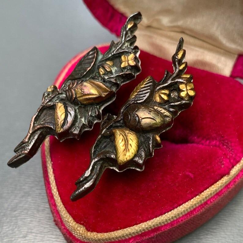 A stunning pair of antique Japanese Shakudo cufflinks, featuring intricate floral designs. Shakudo, a traditional Japanese alloy made of gold and copper, is known for its unique dark bluish-black patina, achieved through a process called rokusho,