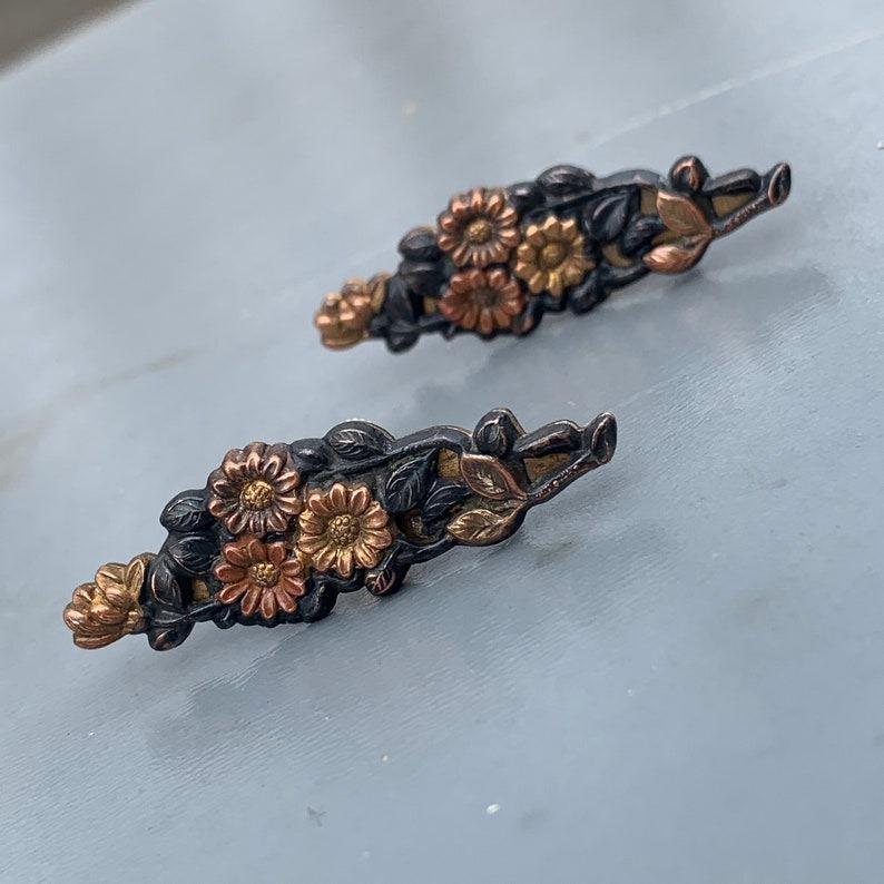 Ein auffälliges Paar antiker japanischer Shakudo-Ohrringe mit einem wunderschön detaillierten Blumen- und Blattmuster. Diese Ohrringe sind aus Shakudo gefertigt, einer traditionellen japanischen Legierung aus Gold und Kupfer, die für ihre