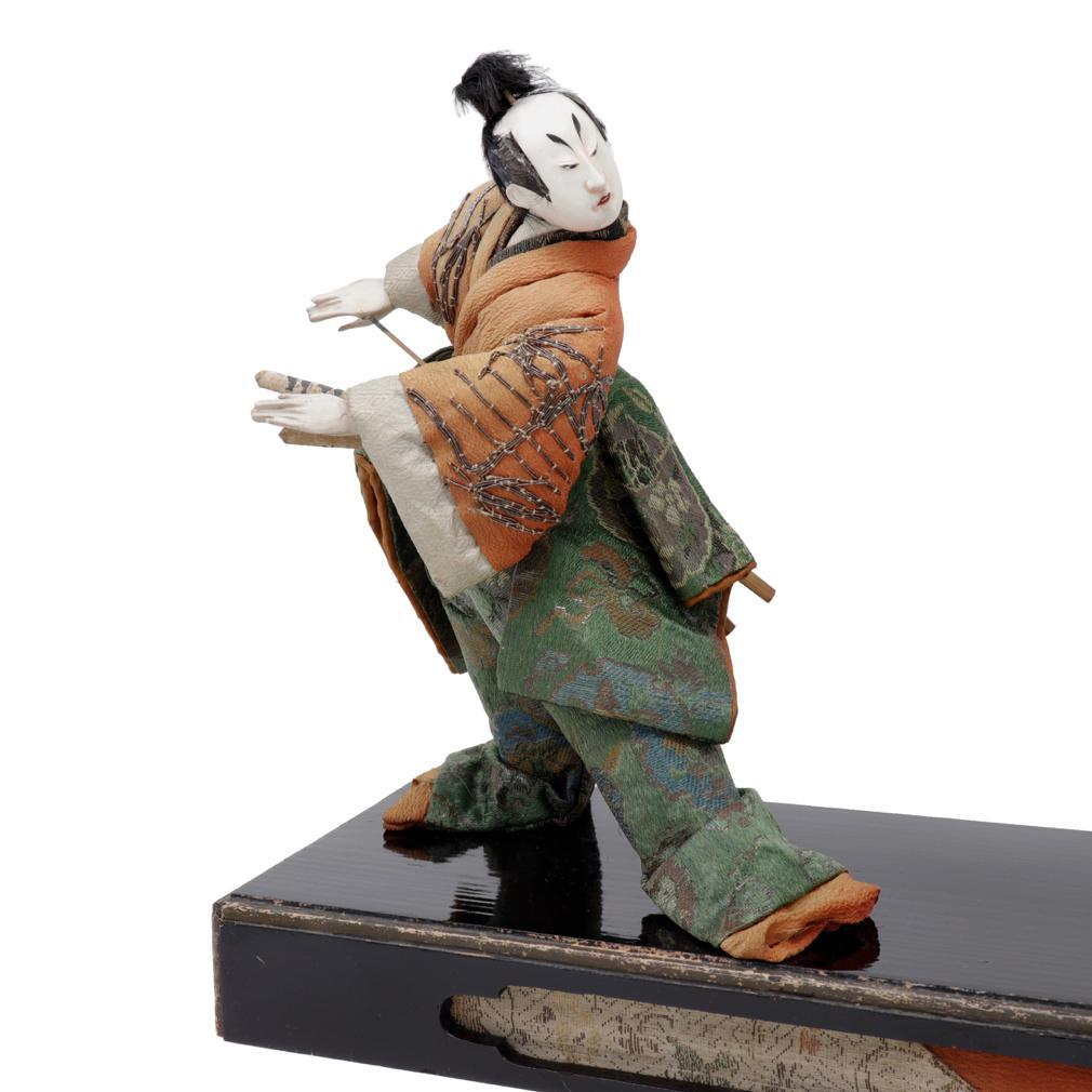 Antique Japanese Takeda Ningyo doll set of two kabuki actors on the stage. Each figure with a wide stance turning to look at one another. The figures are costumed in silks, kinran brocades and birodo velvet, one with long trousers, chirimen sleeves