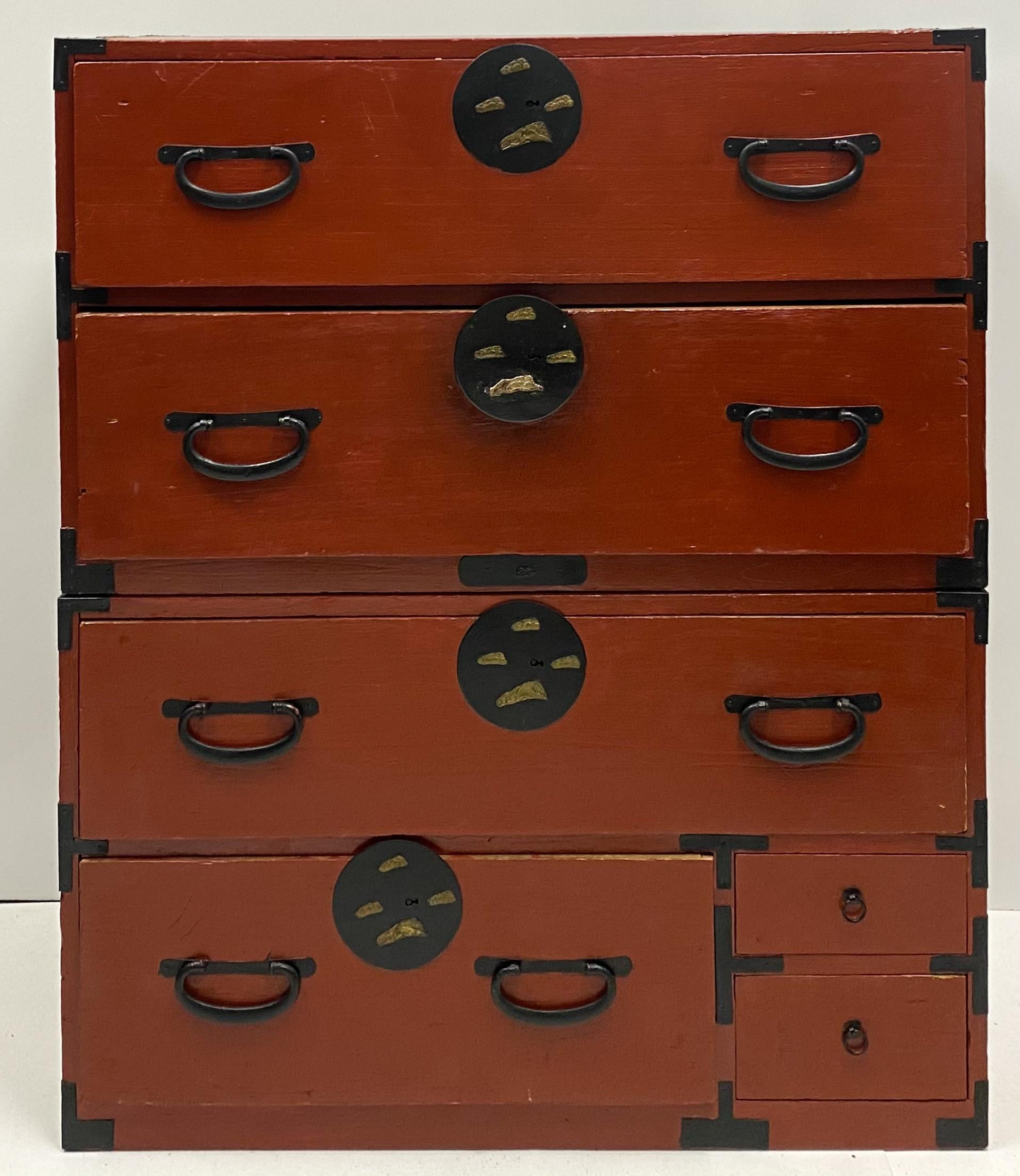 This is an antique Asian Tansu campaign style stacking clothing chest. It has a lacquered burnt orange finish and hand forged hardware with fish motif. This is a 19th century piece and does have some age appropriate wear.