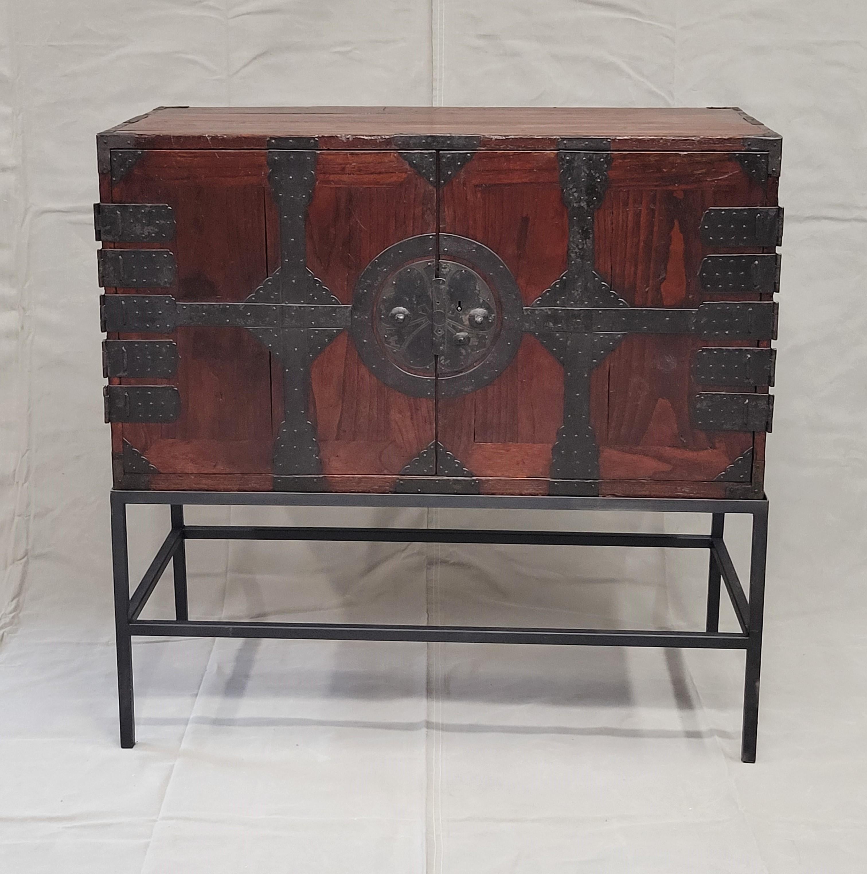 A stunning and unique antique Japanese tansu chest with two interior drawers that sits on a custom made contemporary black metal stand. The tansu chest was part of a larger cabinet which was lost at some point in time. The black iron hardware on the