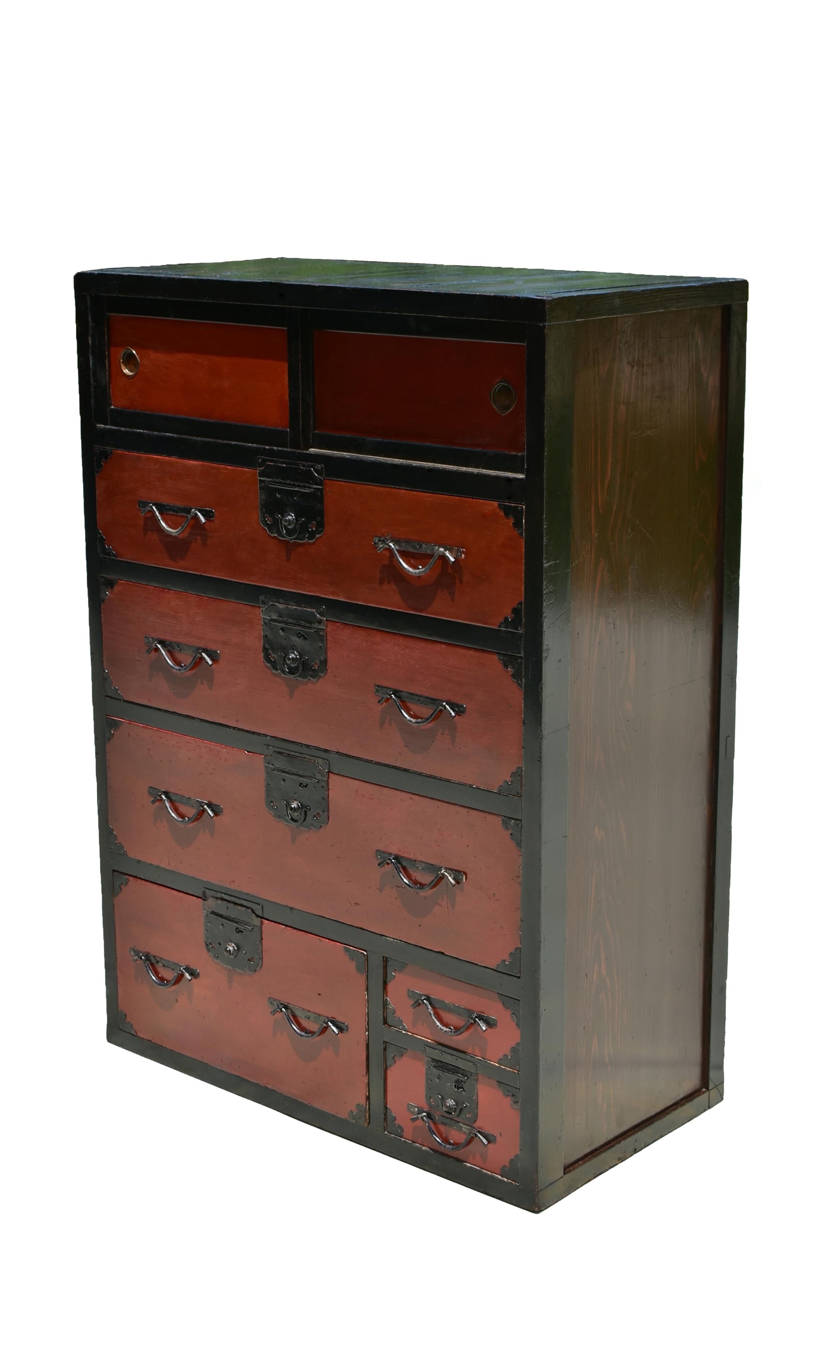 Este precioso Tansu japonés de la época Taisho está lacado en un llamativo bicolor negro y naranja quemado rojizo, que encarna la elegancia de la artesanía tradicional. Un par de puertas correderas ocultan una espaciosa zona de almacenamiento,