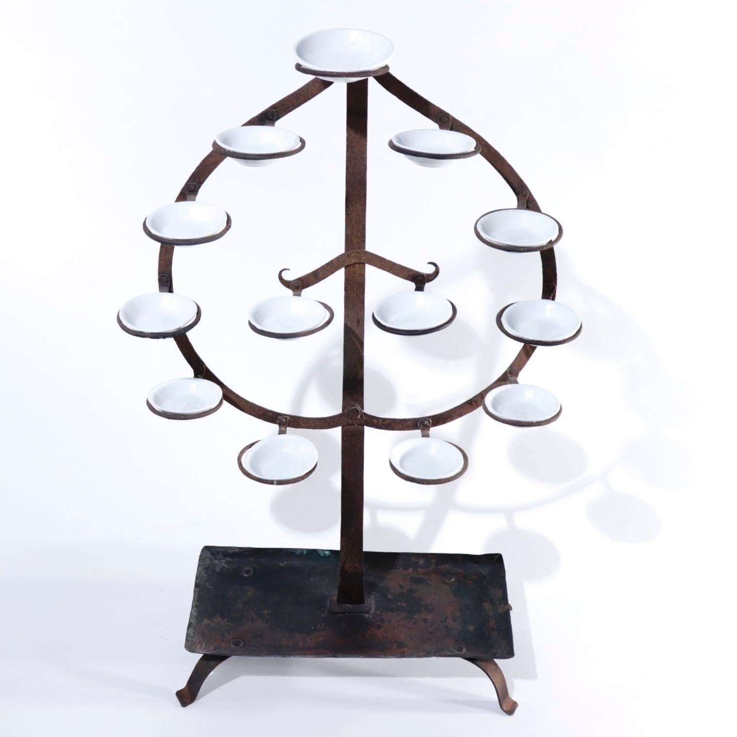 Japanese Tomyodai, a temple light stand created of iron and copper in the upright form of the Tama (Buddhist flaming jewel) with 13 ringlet projections to  hold ceramic oil dishes (replaced), a four legged base with copper pan base. Current day use