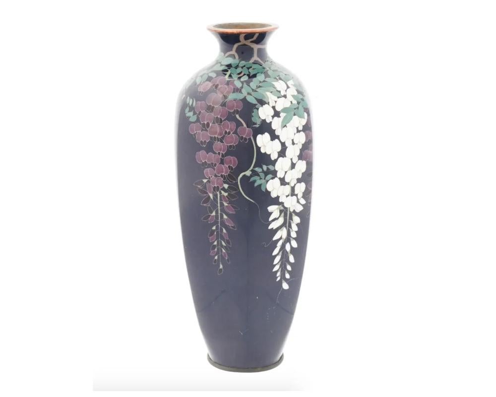 An antique Japanese Meiji period cloisonne vase of a baluster shaped body rising from a slightly spreading foot to a broad waisted neck and everted rim, decorated with flowering boughs of wisteria worked in silver wire and enamels, set against a