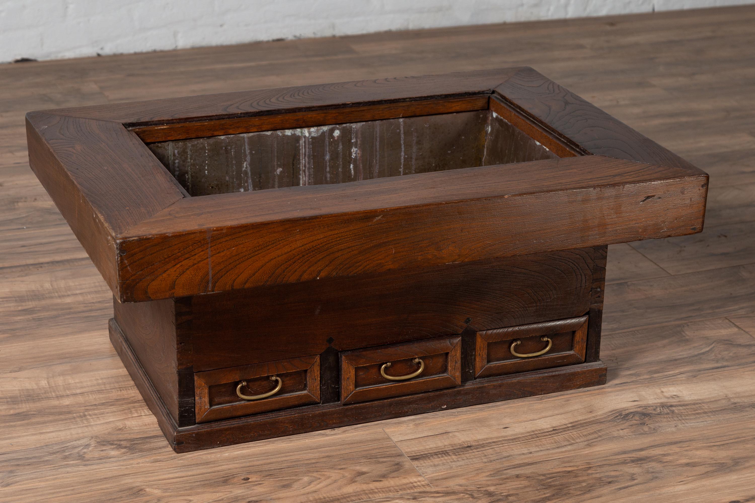 An antique Japanese rectangular wooden hibachi from the early 20th century, with metal liner and three drawers. Used for cooking or warming sake or tea, this elegant hibachi features a rectangular frame with large top surrounding a central opening