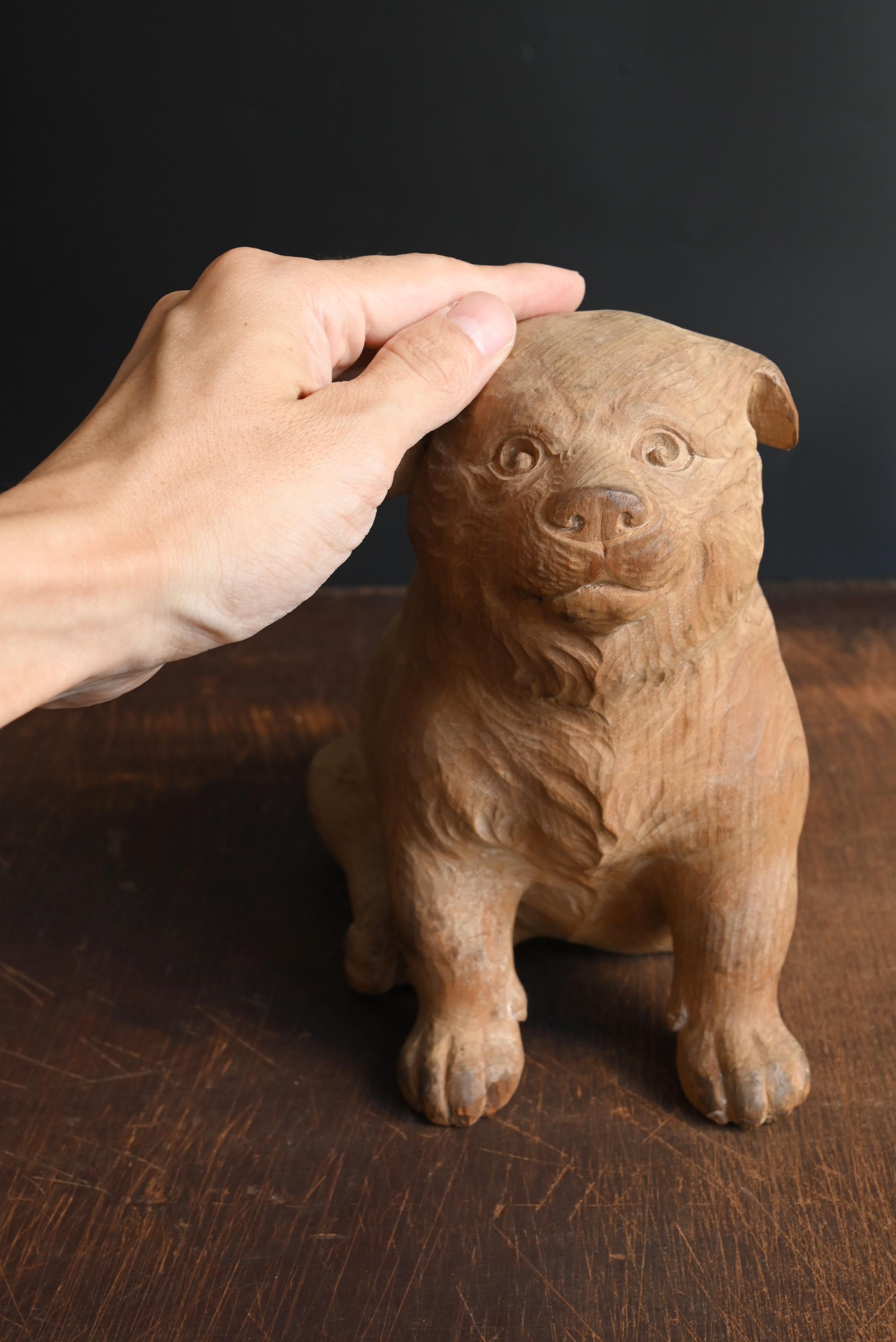 Il s'agit d'une figurine de chiot en bois créée au Japon pendant la période Showa. Fabriqué à partir d'un bois de conifère comme le cyprès, il conserve son grain doux et sa texture chaleureuse. Fini sans vernis, le bois nu met en valeur les marques