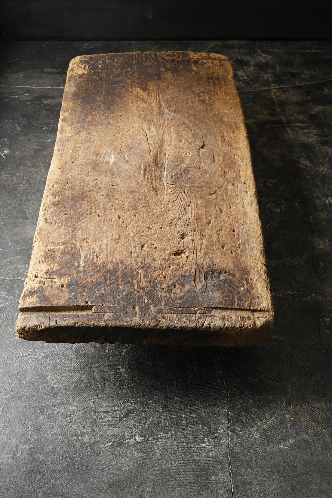Cette table basse dégage une présence unique, avec un plateau fabriqué à partir d'un ancien établi japonais et des pieds fabriqués à partir de poutres d'une ancienne maison japonaise. Le plateau de la table est fabriqué à partir d'une seule pièce de