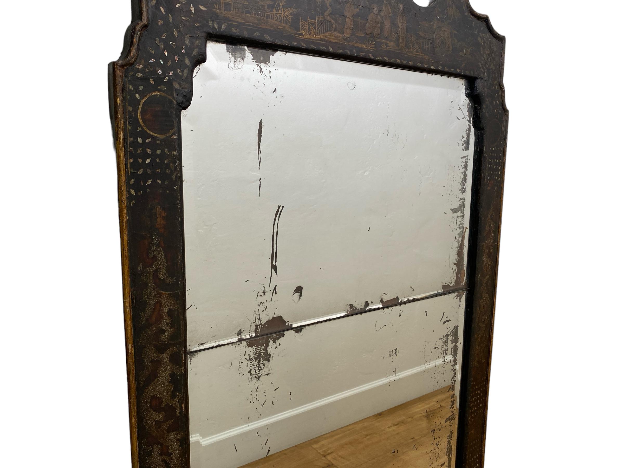 An Antique Japanned Wall Mirror, a rare item that stands as a testament to the exquisite craftsmanship and artistic sensibilities of a bygone era. This captivating piece features a meticulously crafted frame, adorned with intricate figures and