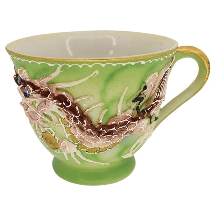 A beautiful artisanal handcrafted porcelain dragonware teacup and saucer set. This set features a moriage dragon design. Created from slip and applied around the body of the cup, the eye-catching dragon is hand-painted in gorgeous red, blue, green,