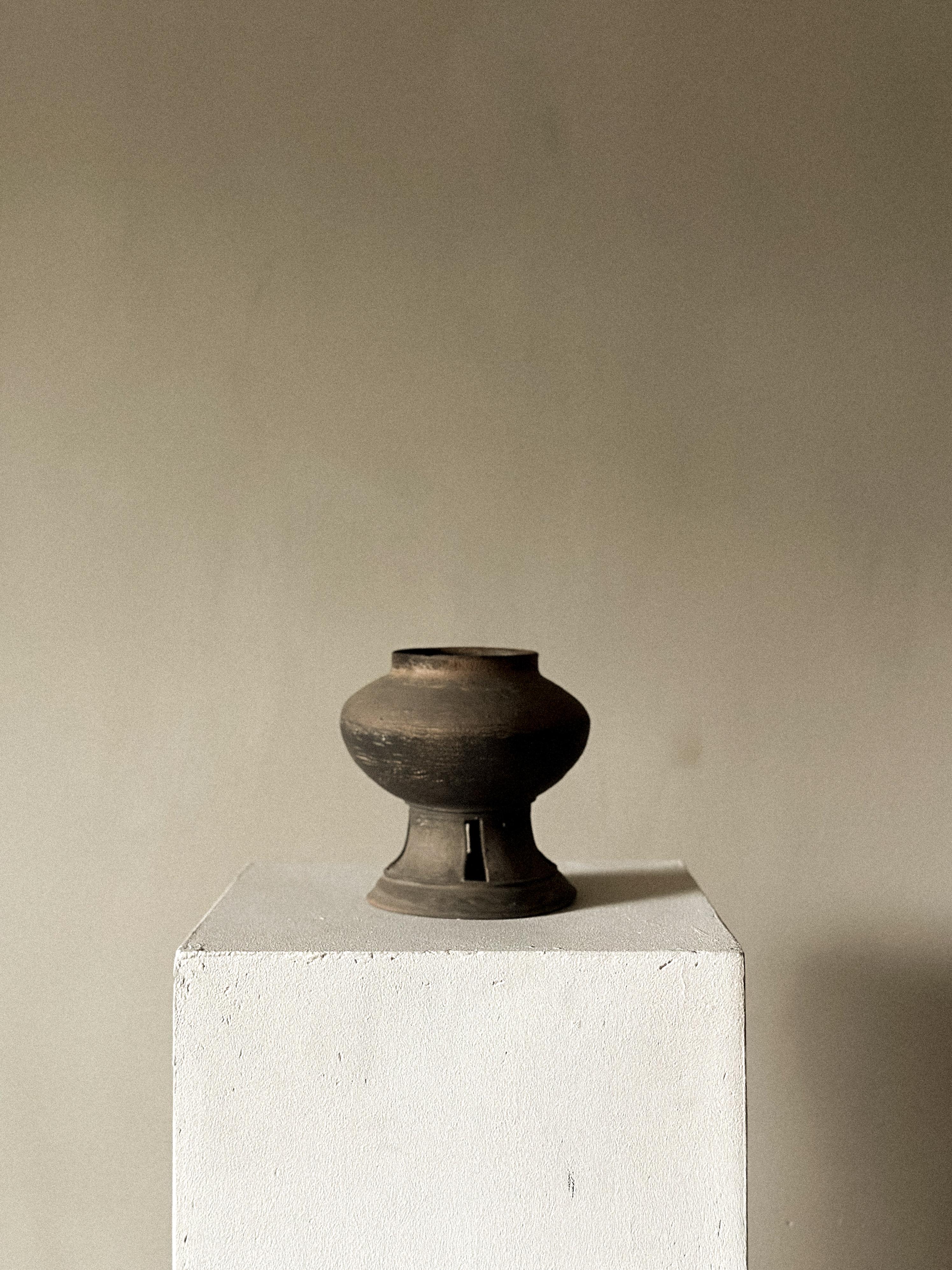 A jar, Silla period (57 BCE – 935 CE). Raised, wide foot with openwork decoration. Impressed decoration on the body. Ash glaze. Wear consistent with age.

PROVENANCE
Johanne Huitfeldt's (1932-2023) collection of Asian ceramics and antiquities.