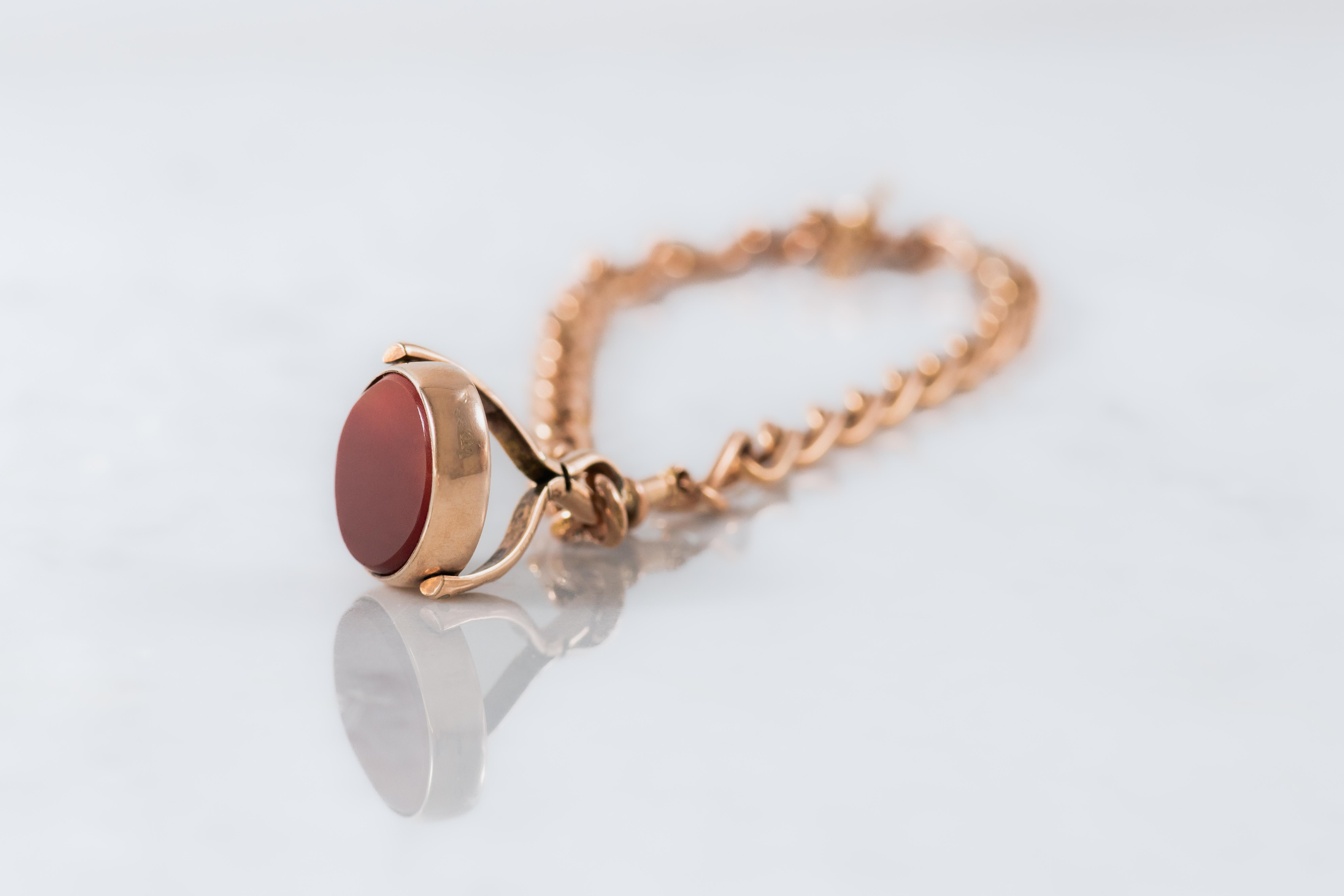 A Bi-coloured fob spinner pendant connected with a rose gold gold dog clip. The shoulders of the spinner are decoratively engraved. Mounted on a rose gold Albert chain with a T bar at the opposite side of the chain. Estimated late 19th to Early 20th