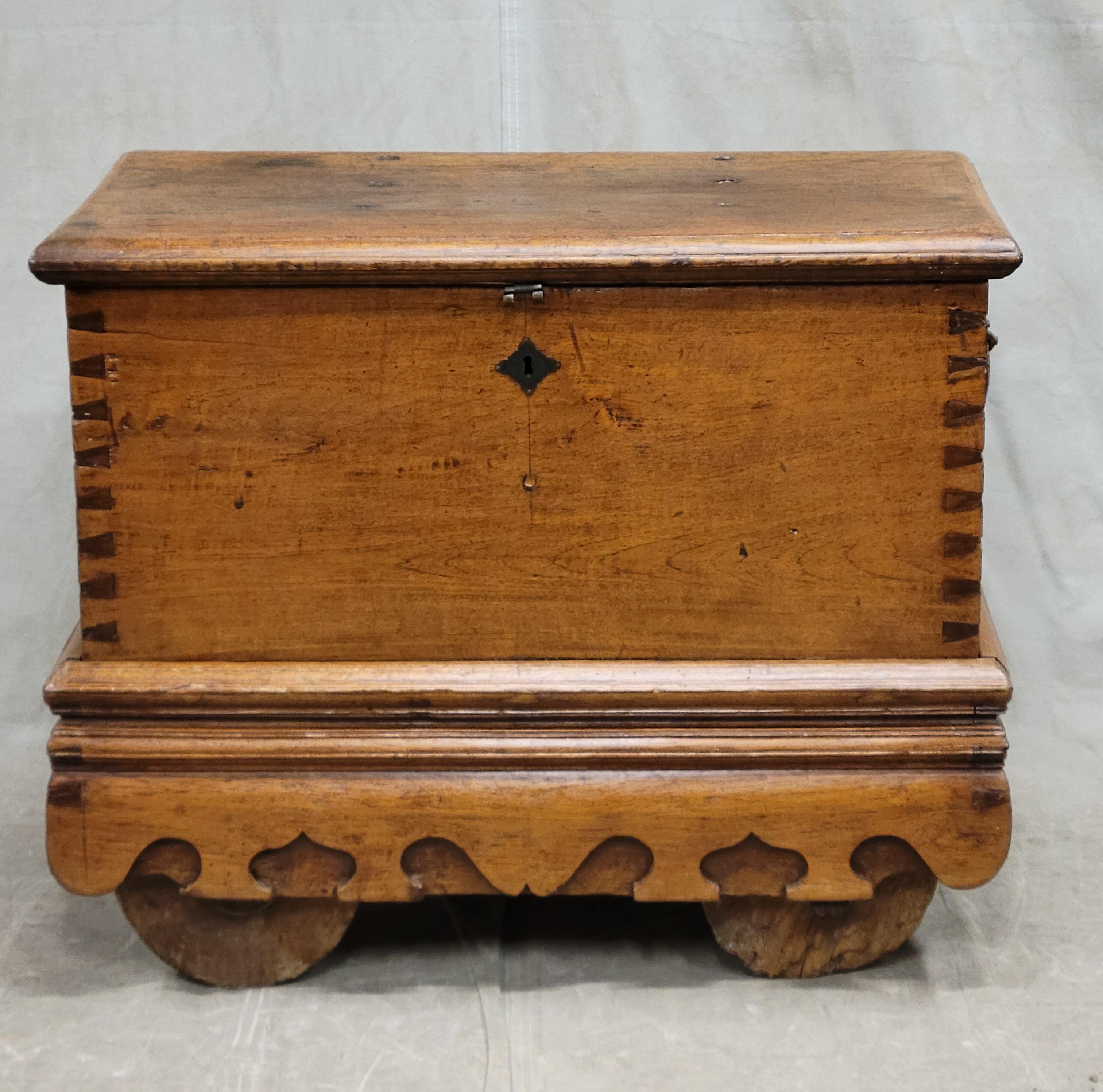 From Java (Indonesia) early 1900s, this dark teak chest has beautiful mortise and tenon joinery, a carved undulating skirt, heavy wood wheels that turn and hand forged iron hardware. The teak has beautiful patina. An interior compartment offers