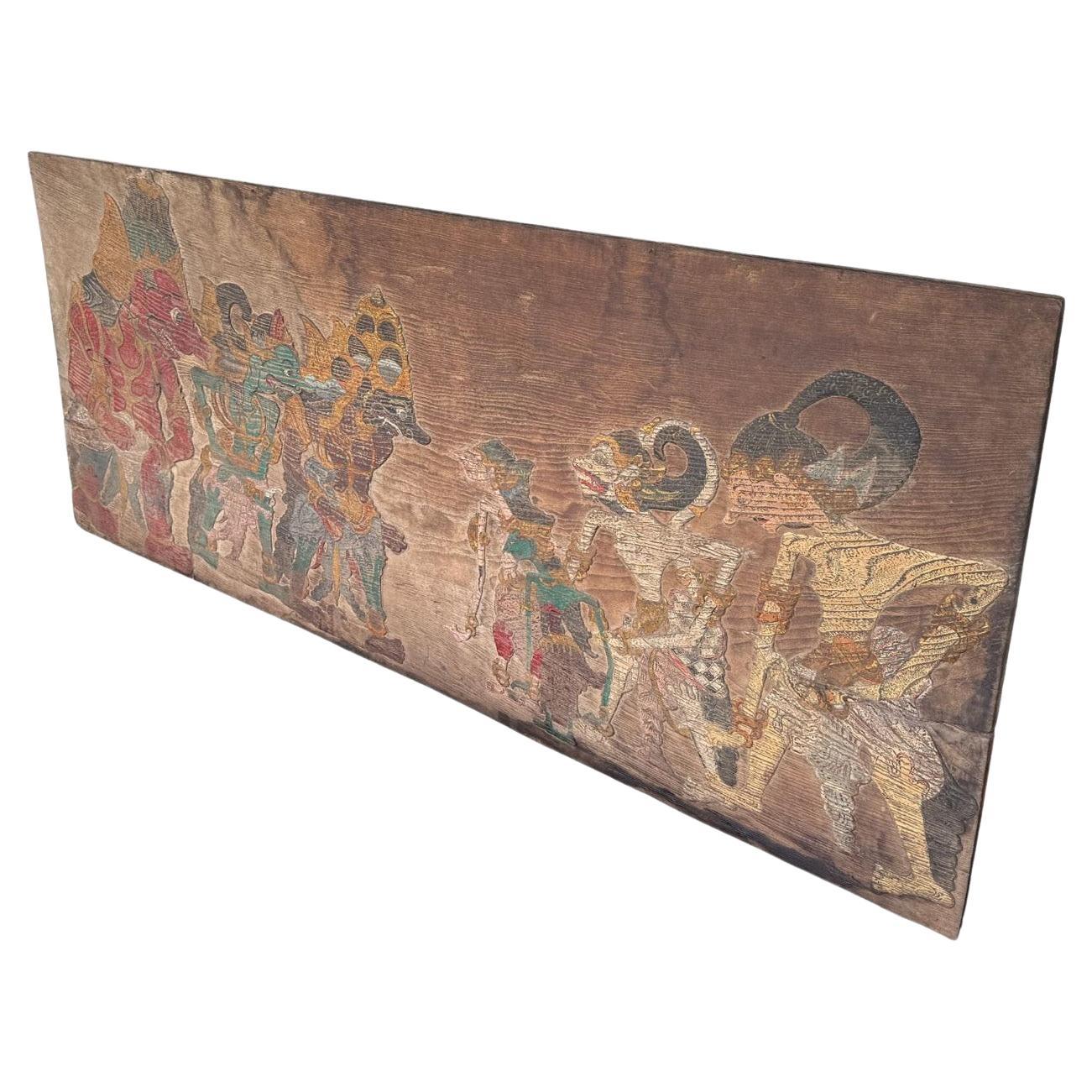 This exquisite antique teak wood panel hails from the culturally rich island of Java, Indonesia, and features a meticulously hand-carved and hand-painted depiction of a Wayang scene — the traditional Javanese shadow puppet theatre that illustrates