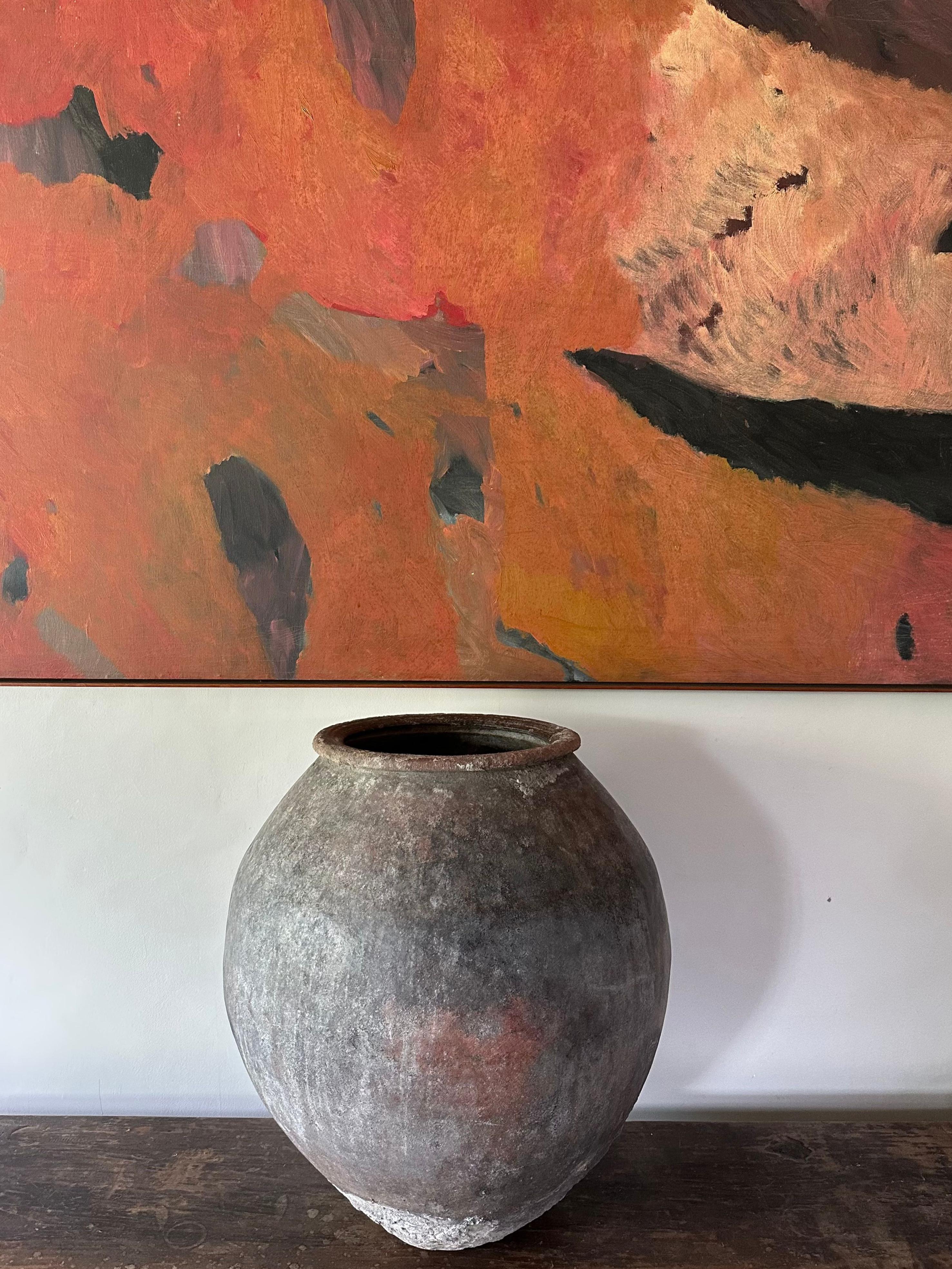 An antique terracotta water jar from Java, Indonesia. It has faded beautifully over the decades with a wonderful mix of textures and shades. The age related patina present on all sides adds to its charm. The perfect object to bring warmth and
