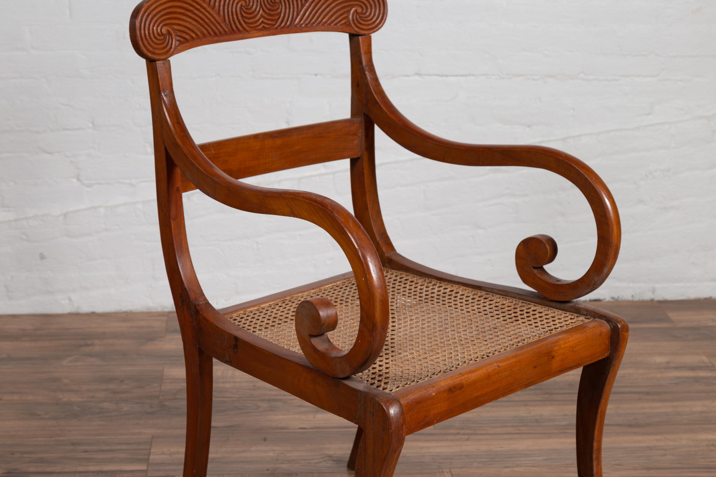 Antique Javanese Wooden Armchair with Carved Back, Curving Arms and Rattan Seat For Sale 2