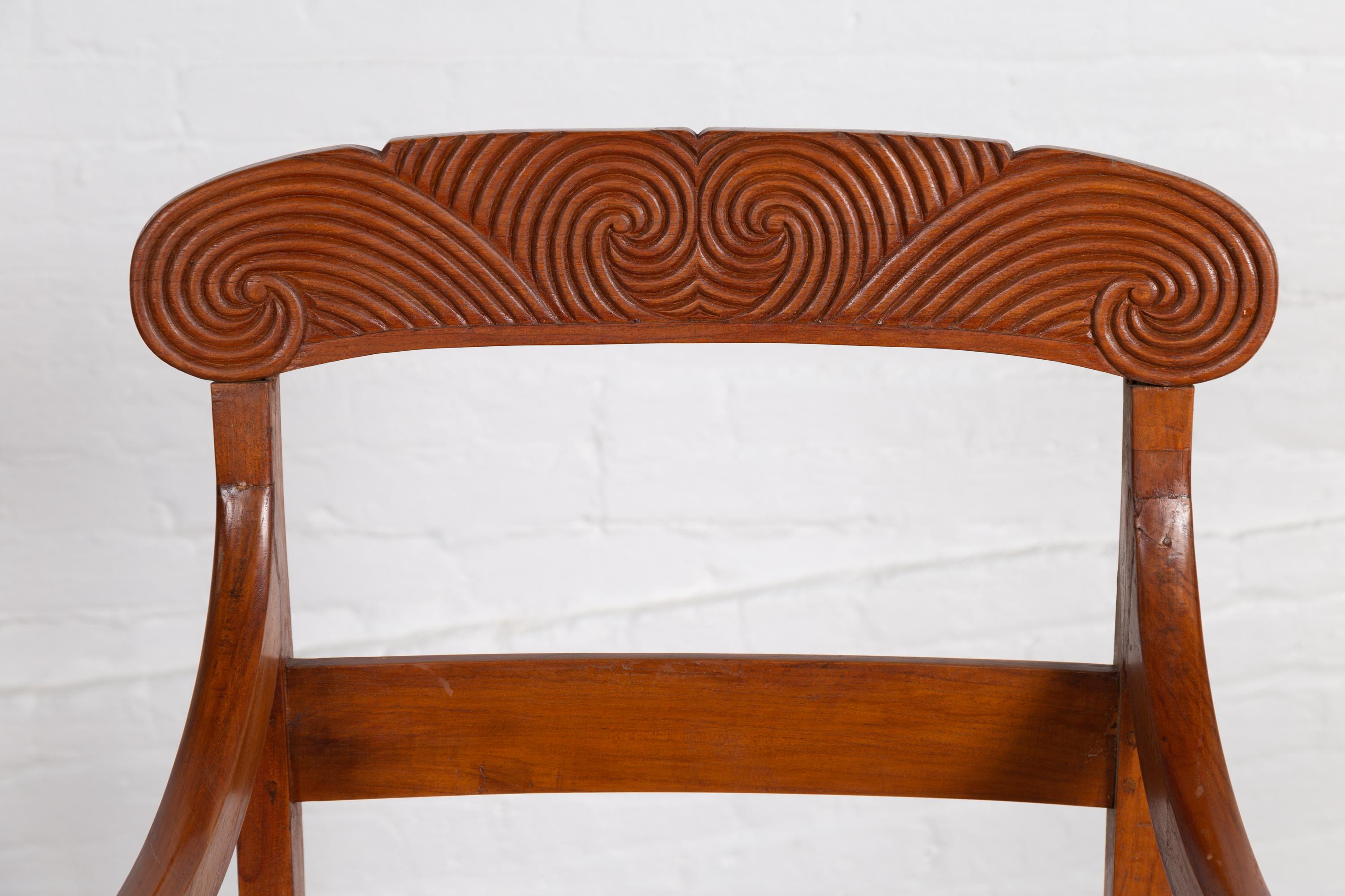 Woven Antique Javanese Wooden Armchair with Carved Back, Curving Arms and Rattan Seat For Sale