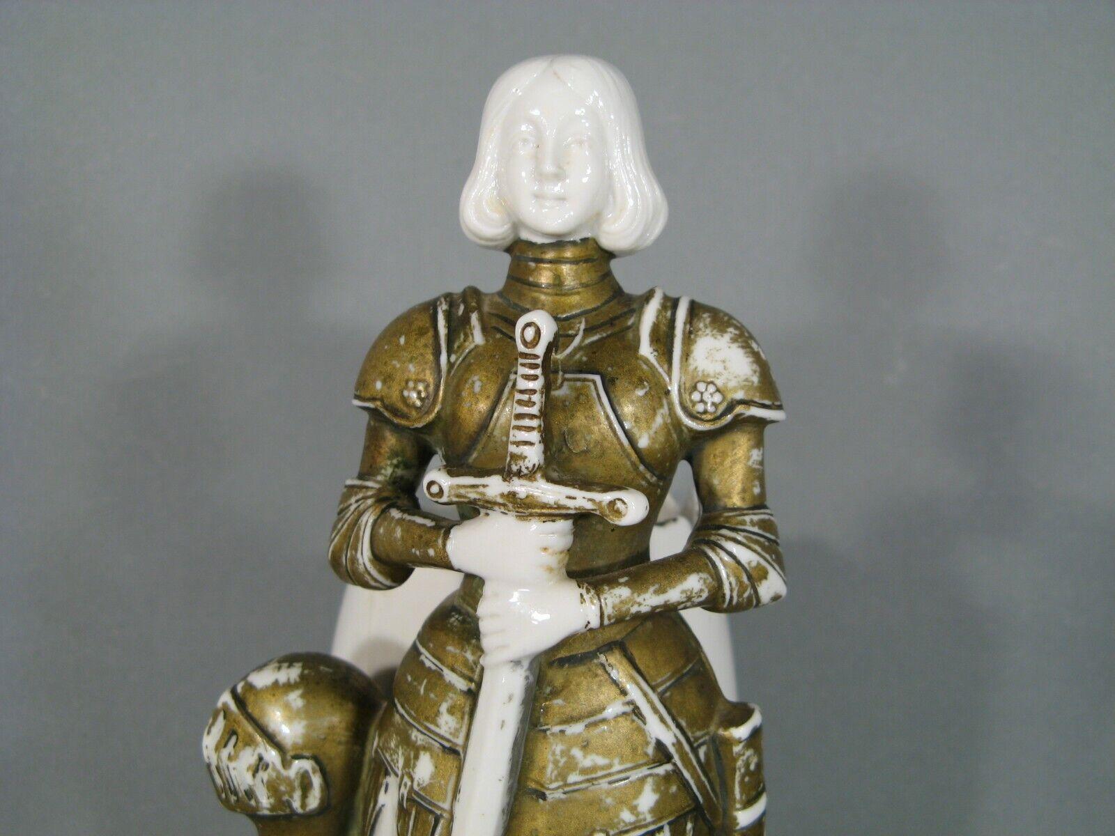 Este jarrón de cerámica antigua presenta una intrincada representación de Juana de Arco con armadura. El jarrón está numerado en la base, lo que resalta su carácter único y coleccionable. Es una pieza elegante con un tema histórico, perfecta para