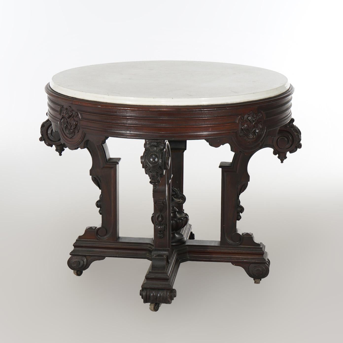 An antique center table in the manner of John Jelliff offers marble top surmounting rosewood base with exaggerated skirt having carved floral reserves, raised on stylized scroll form legs with center urn form finial, c1880

Measures - 30.5
