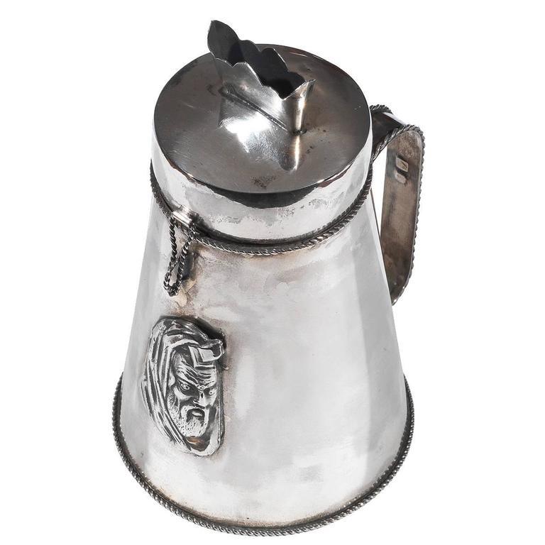 

Russia, silversmith monogram Cyrillic M. F. dated 1896 

Silver tankard-form charity box. The front applied with embossed plaque depicting a rabbi, the cover with latch and insert for the coins, scroll handles,

Marked on base and handles with