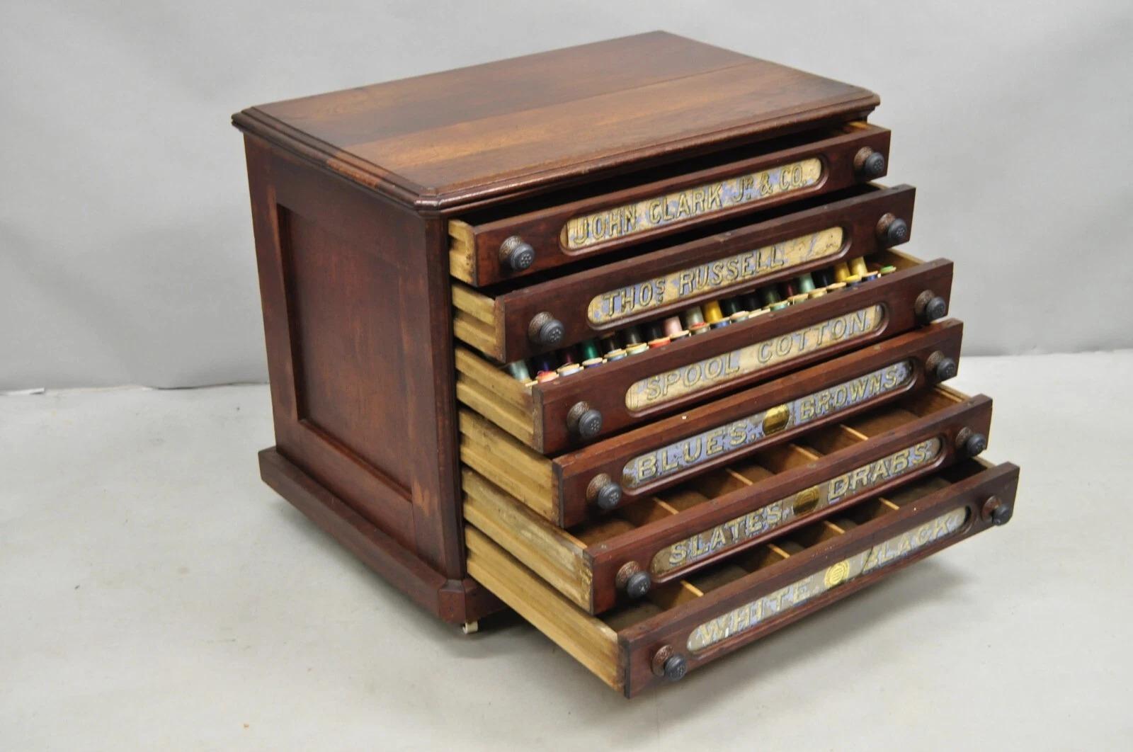 Please message us with your zip code to request a more reasonable domestic U.S. shipping quote.

Antique Victorian John Clark Jr. & Co. Walnut 6 Drawer Sewing Spool Chest Cabinet w/ Reverse Painted Glass and Contents on Wheels. Circa Early 20th