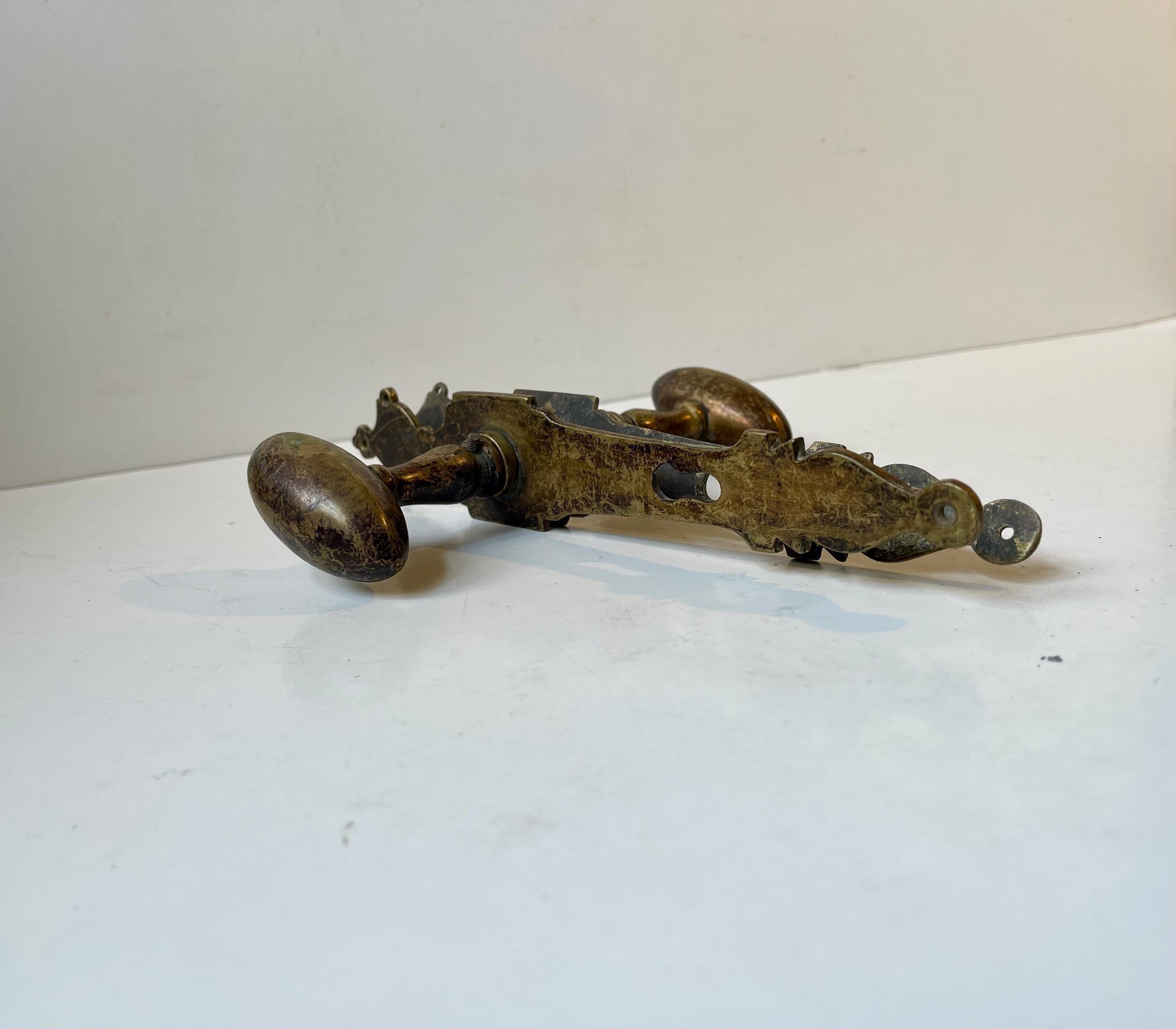 Door handle set with ornamental lock/key covers in patinated brass. The oval brass spindles are thick and rounded of softly due to excessive use over the years. Suitable for your office, conservatory, Atrium, bathroom etc. It was manufactured circa