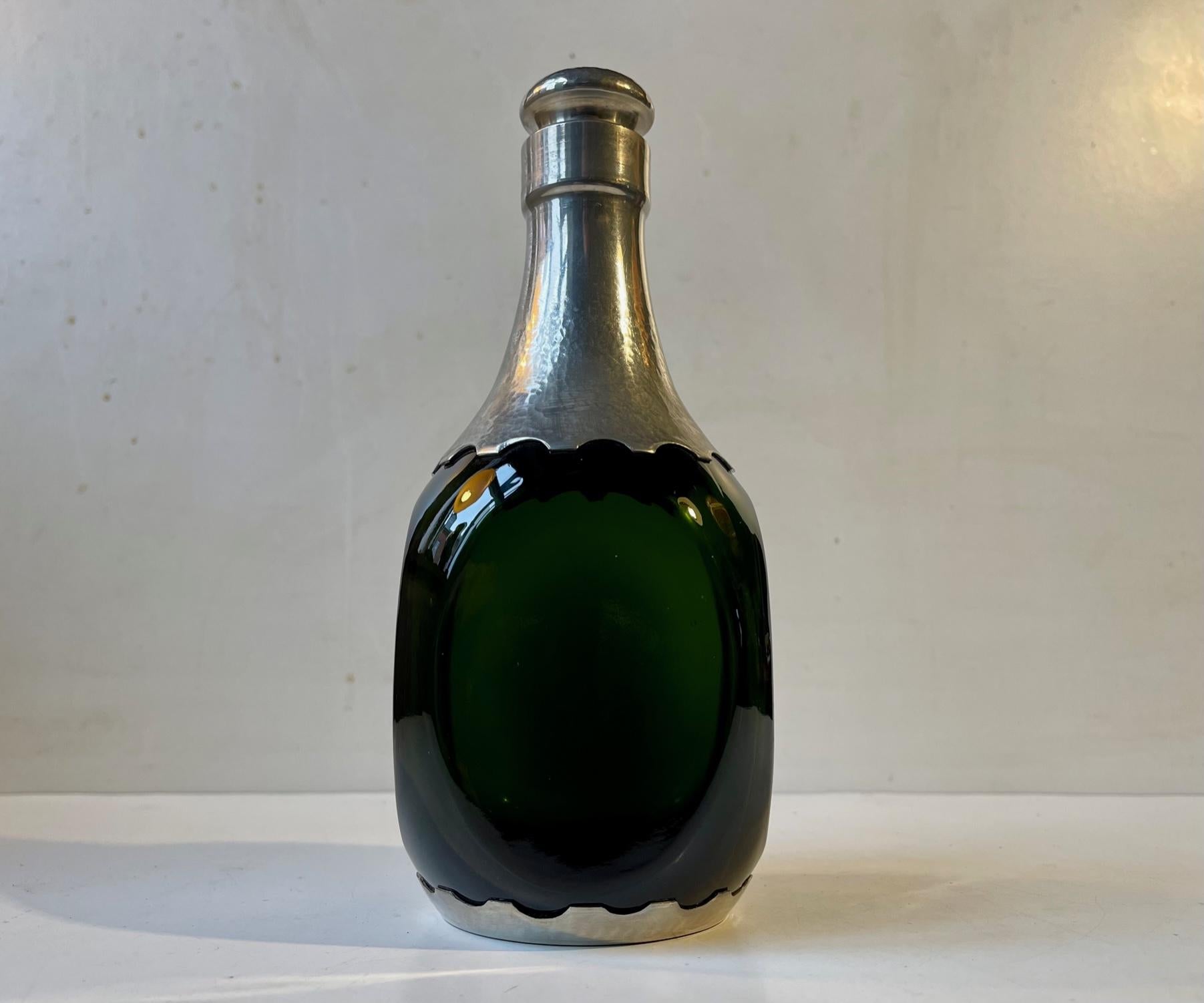 A rare beautiful decanter in green hand-blown glass. Decorated with hand-set/fitted with panels of hammered pewter. Original stopper in pewter and cork. Distinct Danish Jugendstil - art nouveau styling reminiscent of Thorvald Bindesbøll and Mogens