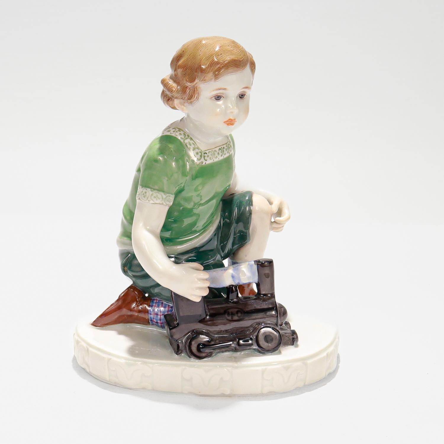 A fine art nouveau porcelain figurine

By the Meissen Porcelain Manufactory.

Modeled by Erich Oehme.

 From the series of Oehme's Meissen child figurines.

Depicting a child (boy) kneeling and holding a toy locomotive train to his right and with a