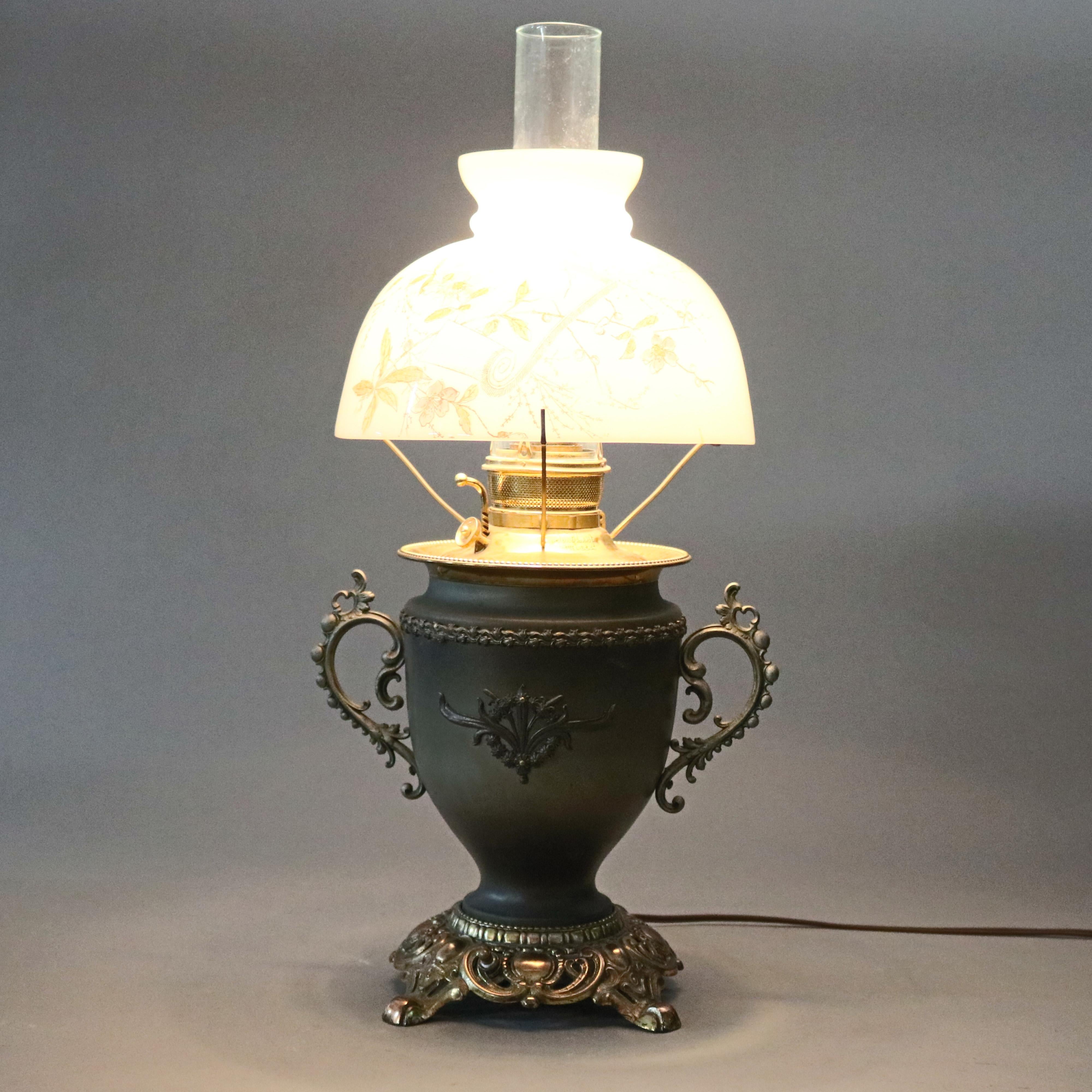 An antique Victorian Rayo style table lamp offers floral painted glass shade surmounting gilt metal double handle base, signed as photographed, c1890.

Measures: 23