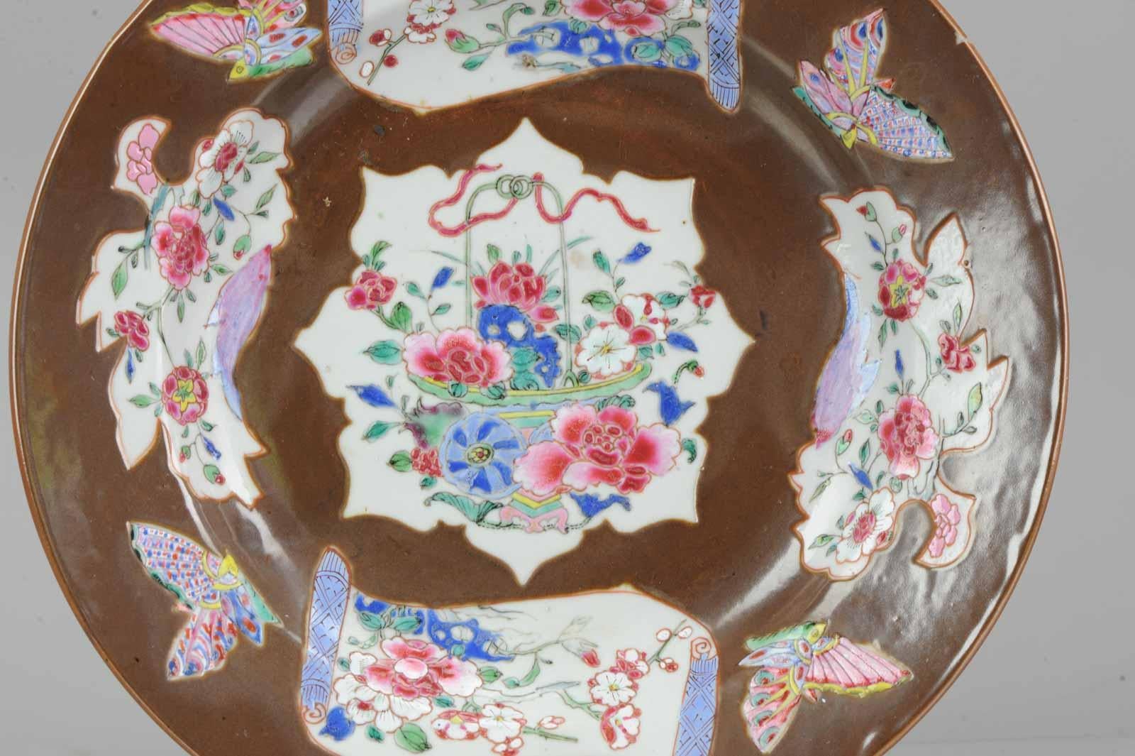 A very nicely made dish with a beautiful decoration.

Batavia brown

A decorative style within Chinese export porcelain using a surface covering brown glaze with or without panels in conjunction with underglaze blue or enamels. The wares appear
