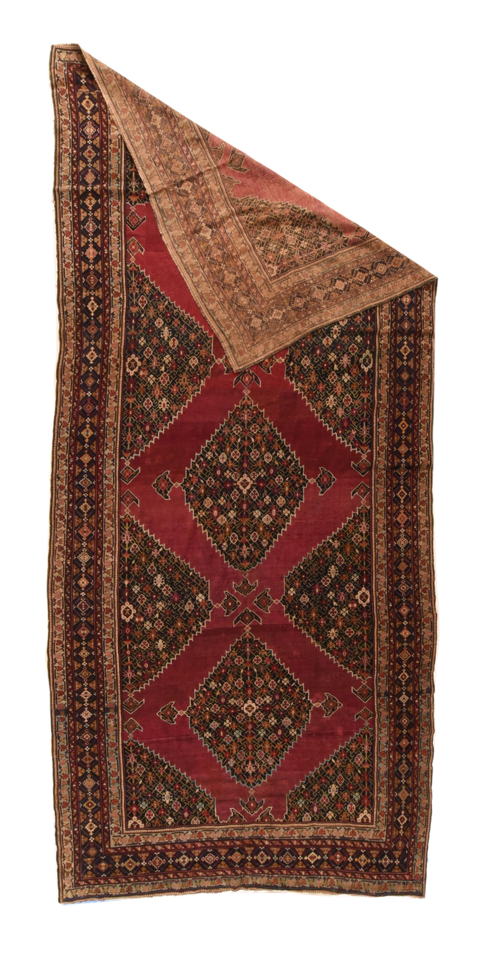 Three complete and eight fractional navy stepped millefleurs hexagonal four pendant medallions float on the plain cochineal scarlet field of this moderately woven, wool foundation south Caucasian workshop carpet, probably from Shusha. Navy border