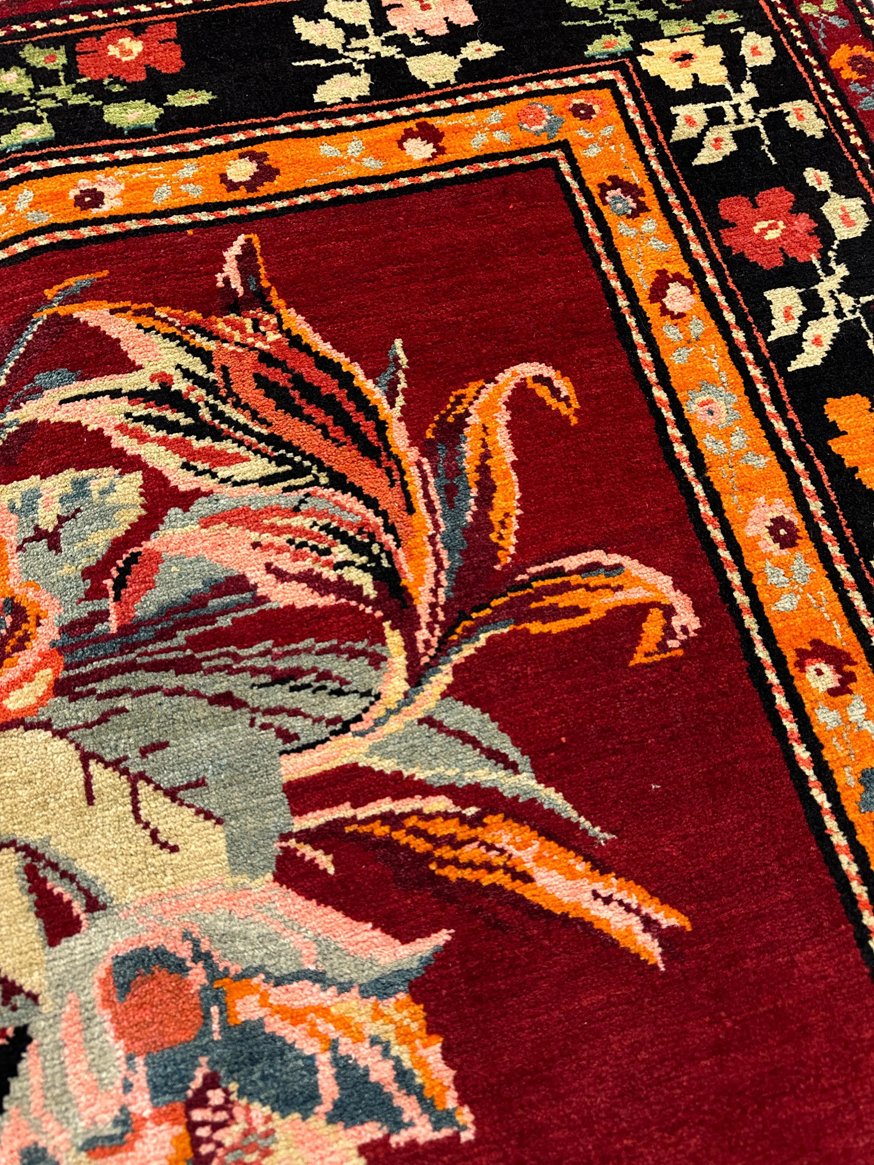 Un intricato bordo scuro incornicia il fondo cremisi di questo runner antico in lana di Karabagh. Presenta un campo di bouquet e motivi floreali ornati con colori saturi che creano un contrasto intrigante e una composizione sorprendente. 
L'usura è