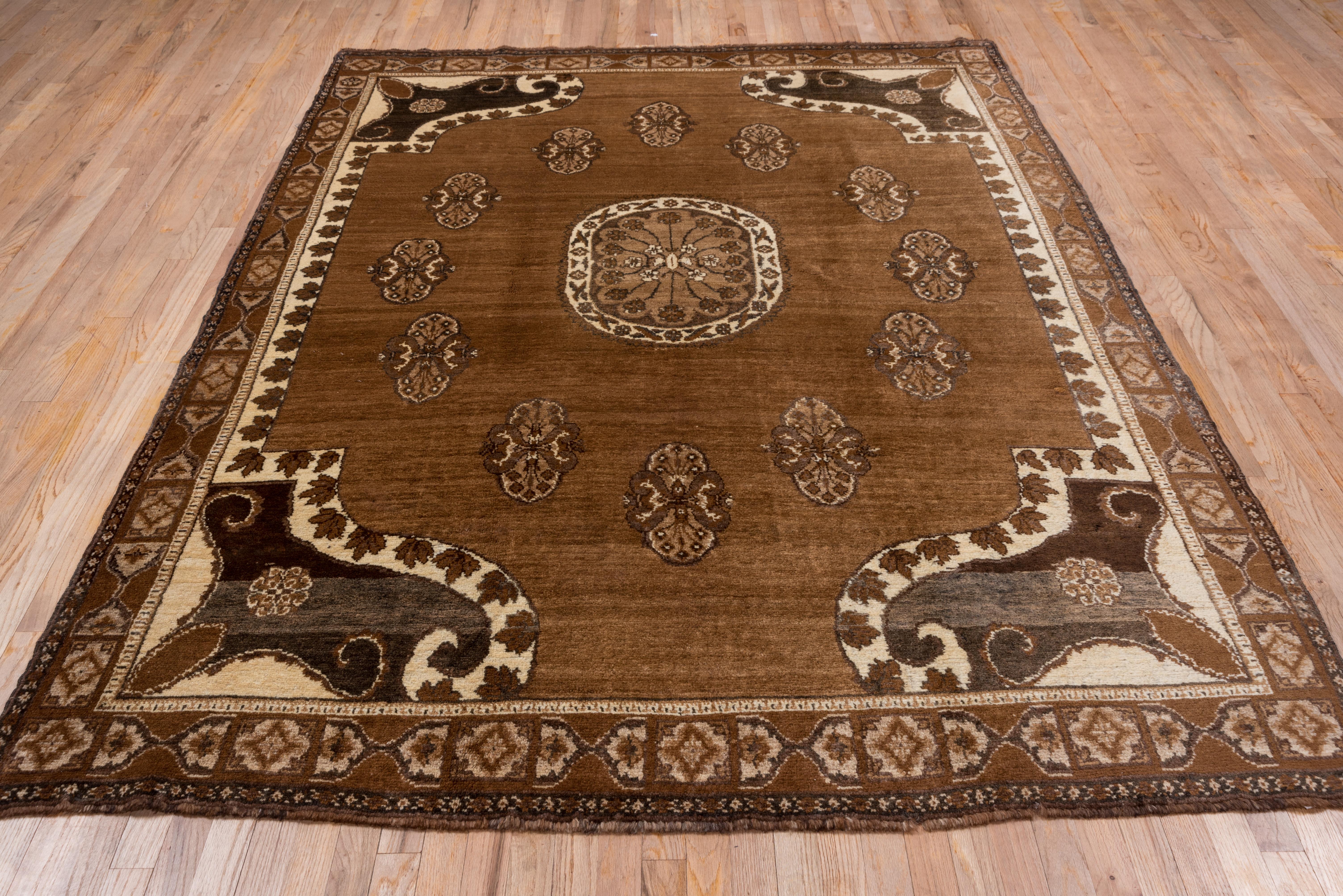 This eastern Anatolian carpet shows a pleasingly abrashed red-brown cartouche-shaped Sub field centred by an ivory disc medallion. The warm old ivory surrounding field features volute scroll corners with rosettes. The olive brown main border shows