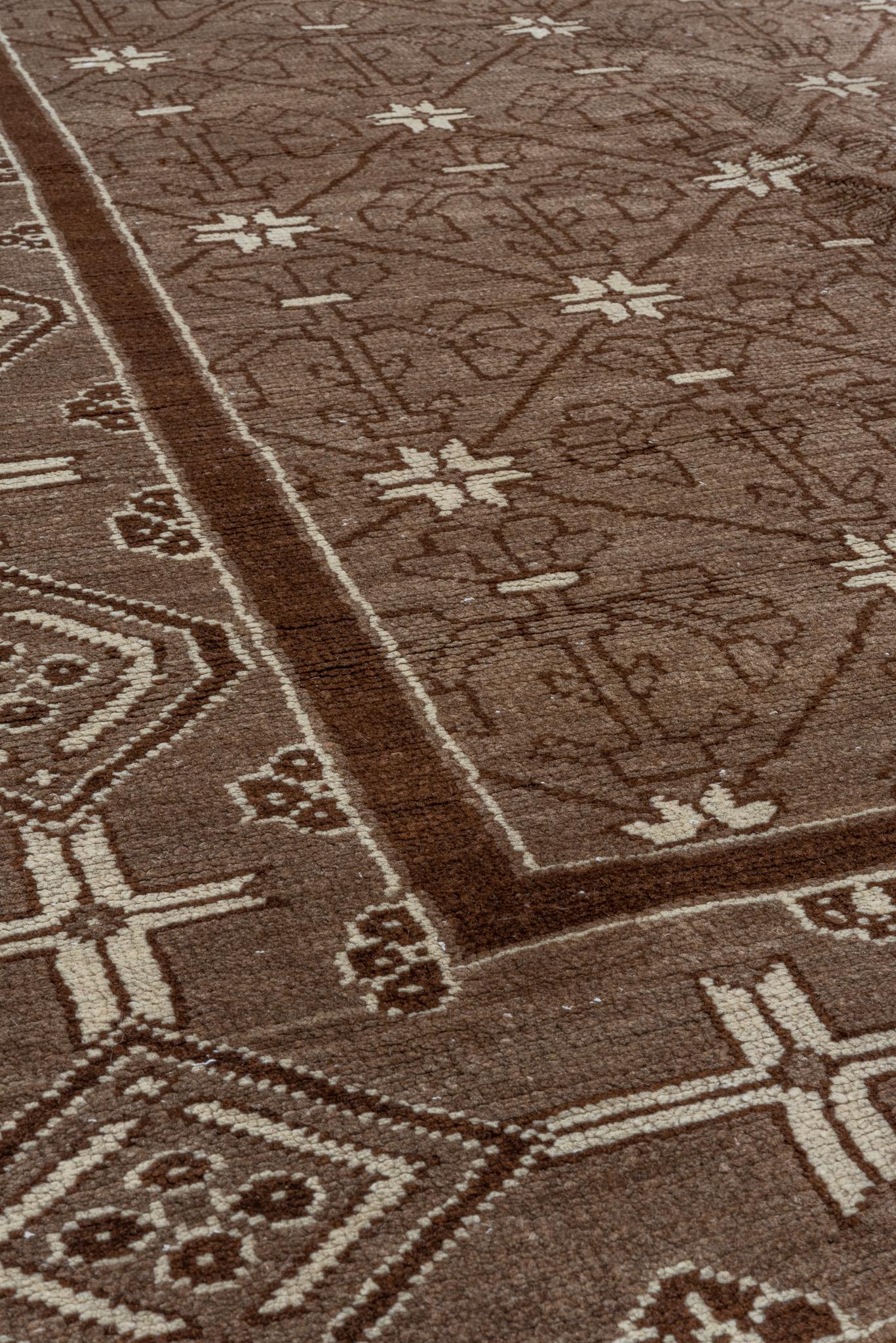 Dieser unverwechselbare Teppich besticht durch seine geometrische Anmutung und sein raffiniertes Gittermuster, das eine Atmosphäre von Symmetrie und schlichter Eleganz schafft. Das Feld zeigt ein zartes Gitter aus sich wiederholenden Motiven in