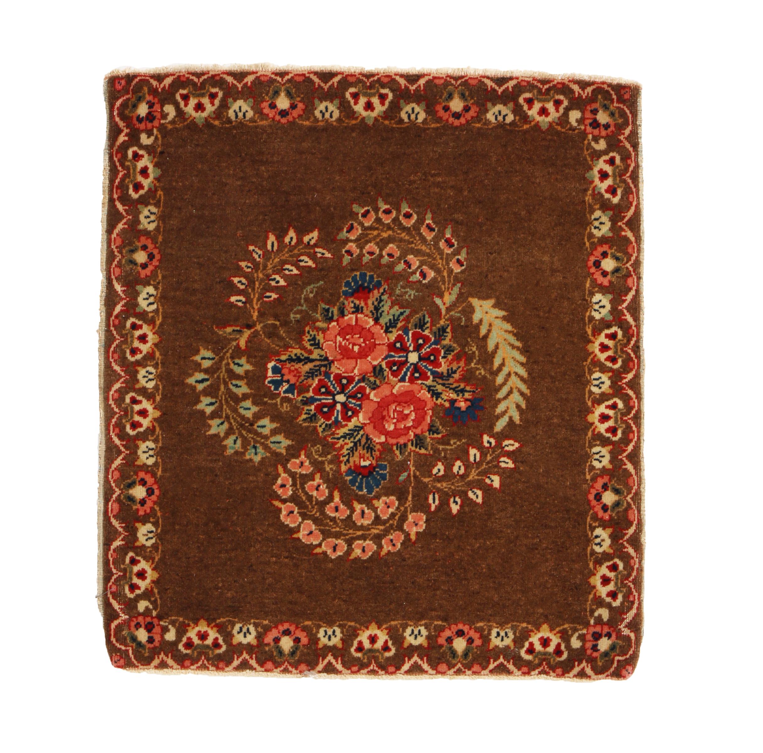 Originating from Persia in 1900, this hand knotted wool antique Persian rug enjoys a distinguished classical combination of rich brown, vivid pink and bright green colorways throughout an abrash field, complemented by highly stylized carnation
