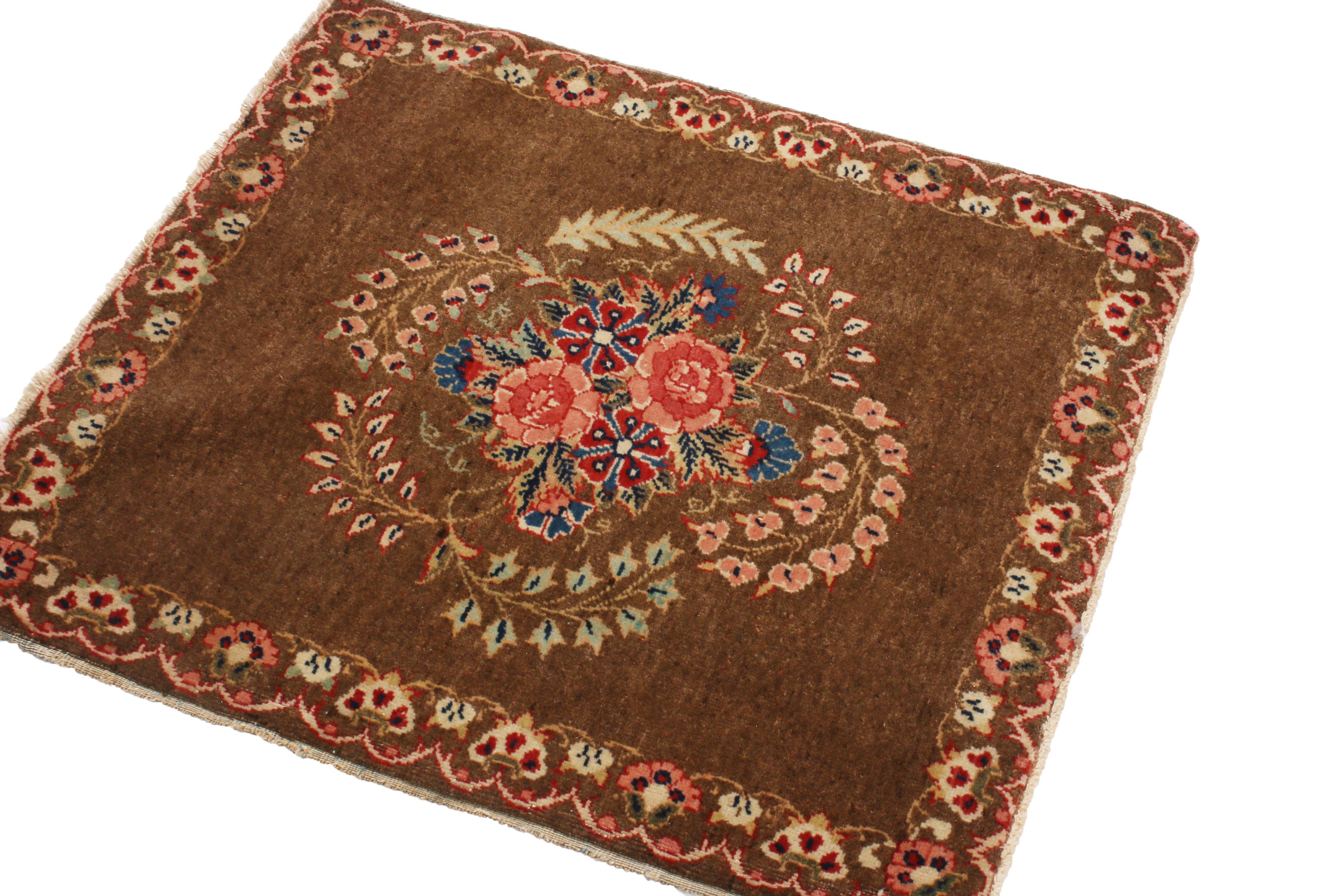 Originating from Persia in 1900, this hand-knotted wool antique Persian rug enjoys a distinguished classical combination of rich brown, vivid pink, and bright green colorways throughout an Abrash field, complemented by highly stylized carnation