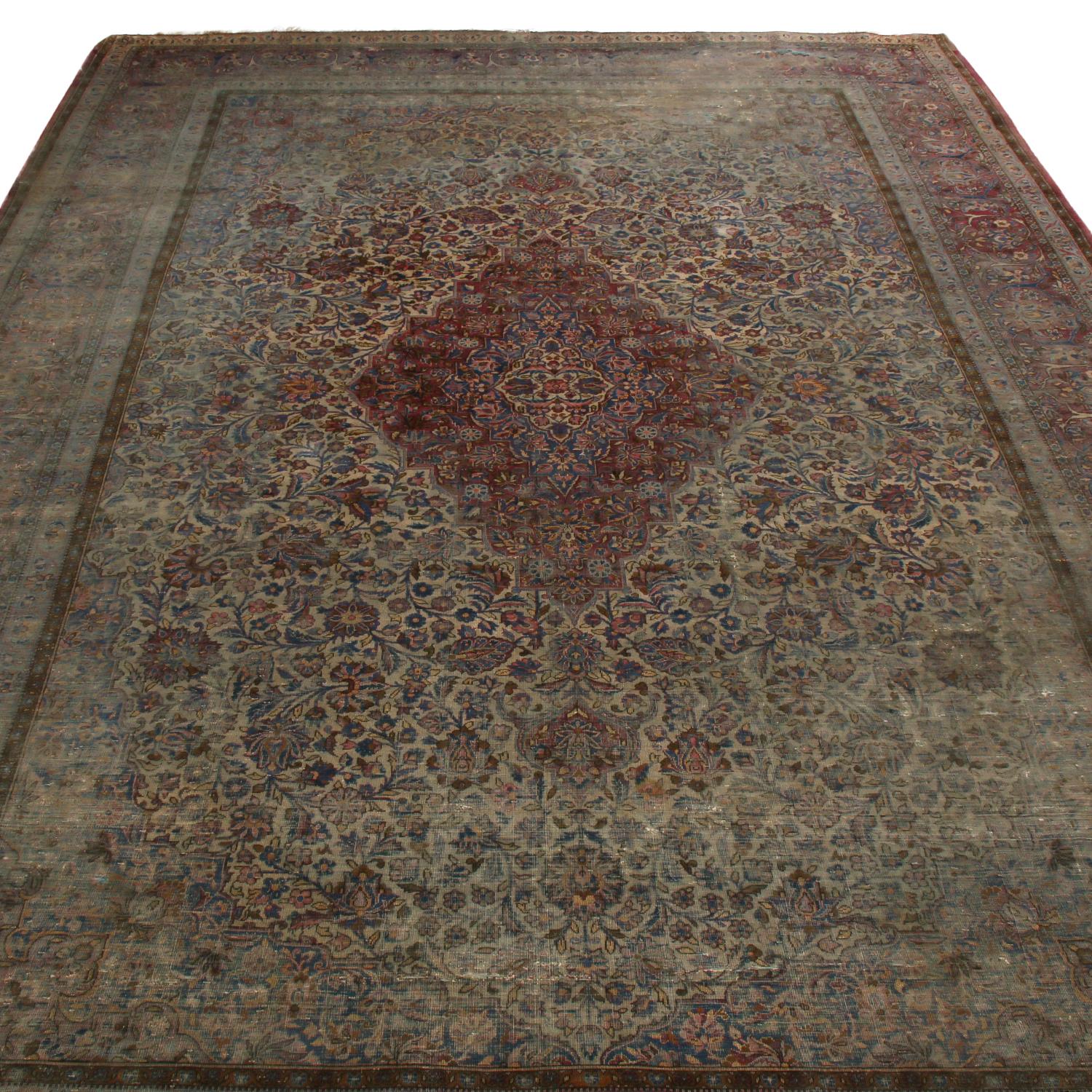Originating from Persia in 1870, this antique Kashan Persian rug enjoys a medallion-style field design with a rich, finely distributed array of burgundy red, frost blue, and silver-beige colorways complemented by floral elements of pink, purple, and