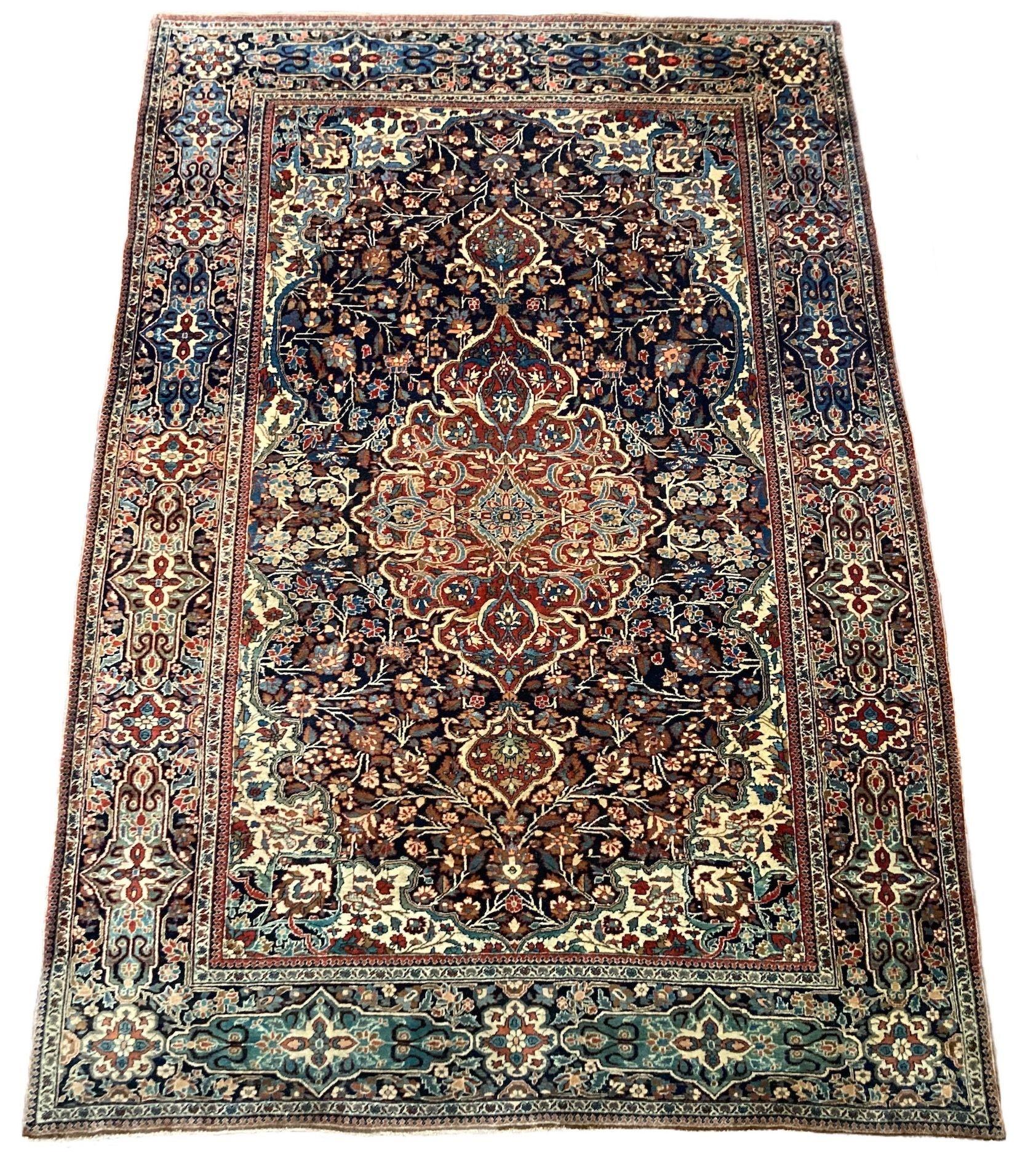 A lovely antique Kashan rug, handwoven circa 1900 featuring a floral design on a deep indigo field around an elegant terracotta medallion and similar border. Fabulous secondary colours, especially the light green and gold throughout the rug. Very