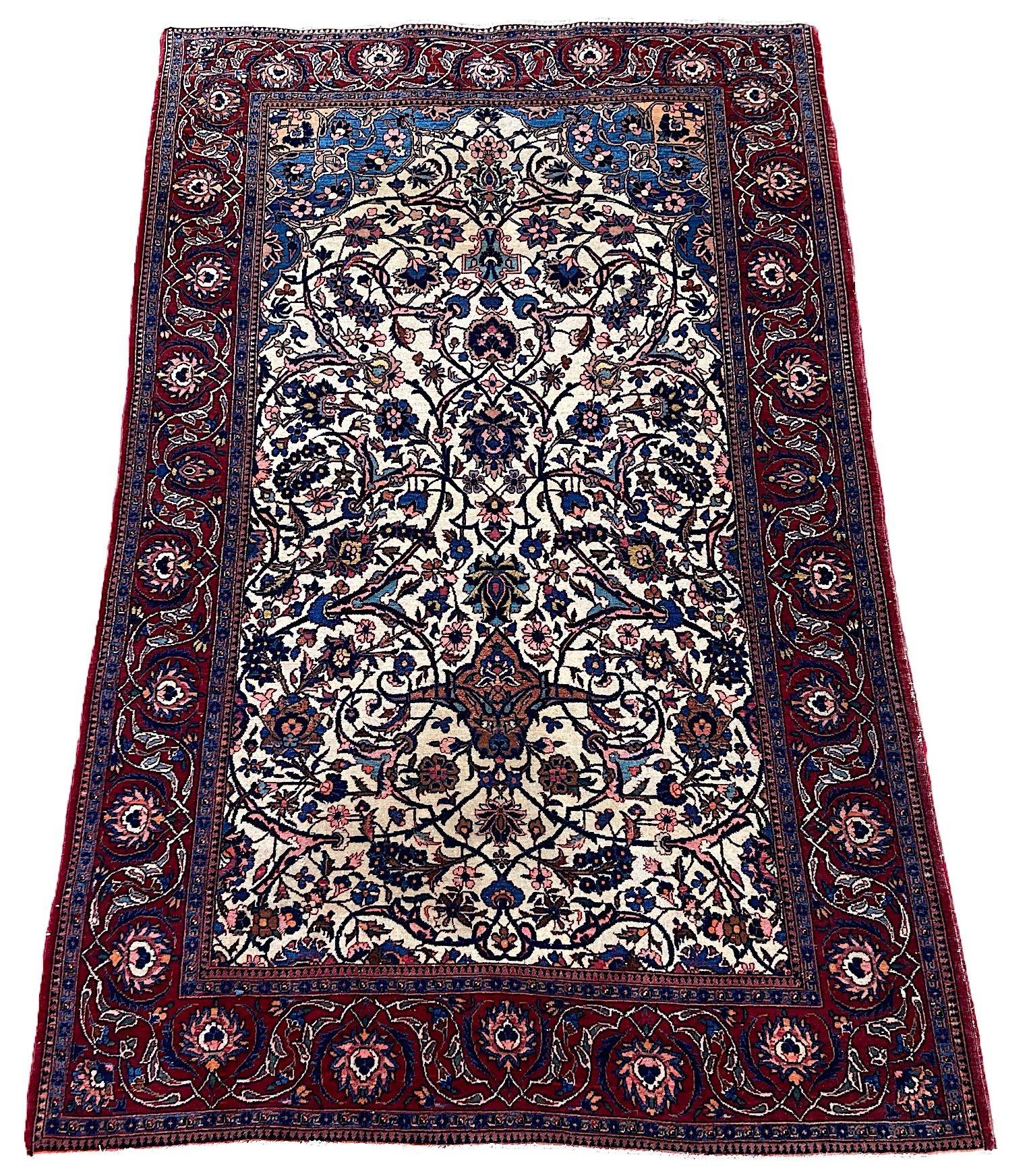 A wonderful antique Kashan rug, hand woven circa 1920. The rug features an all over design of large flower heads and palmettes connected by scrolling vines and arabesques on an uncommon ivory field and red border. An elegantly drawn design with
