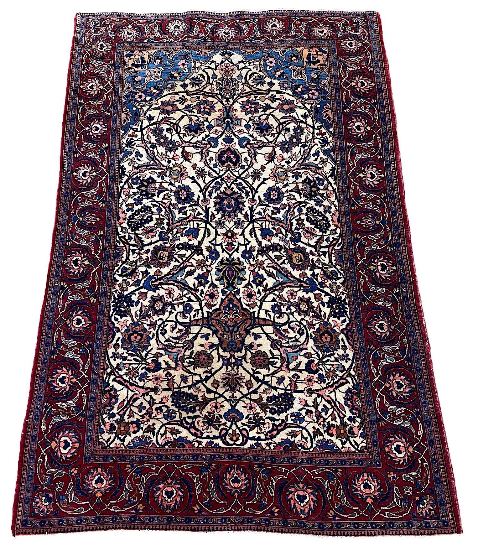 Un meraviglioso tappeto Kashan antico, tessuto a mano intorno al 1920. Il tappeto presenta un disegno all over di grandi teste di fiori e palmette collegate da tralci e arabeschi su un insolito campo avorio e un bordo rosso. Un disegno elegante con